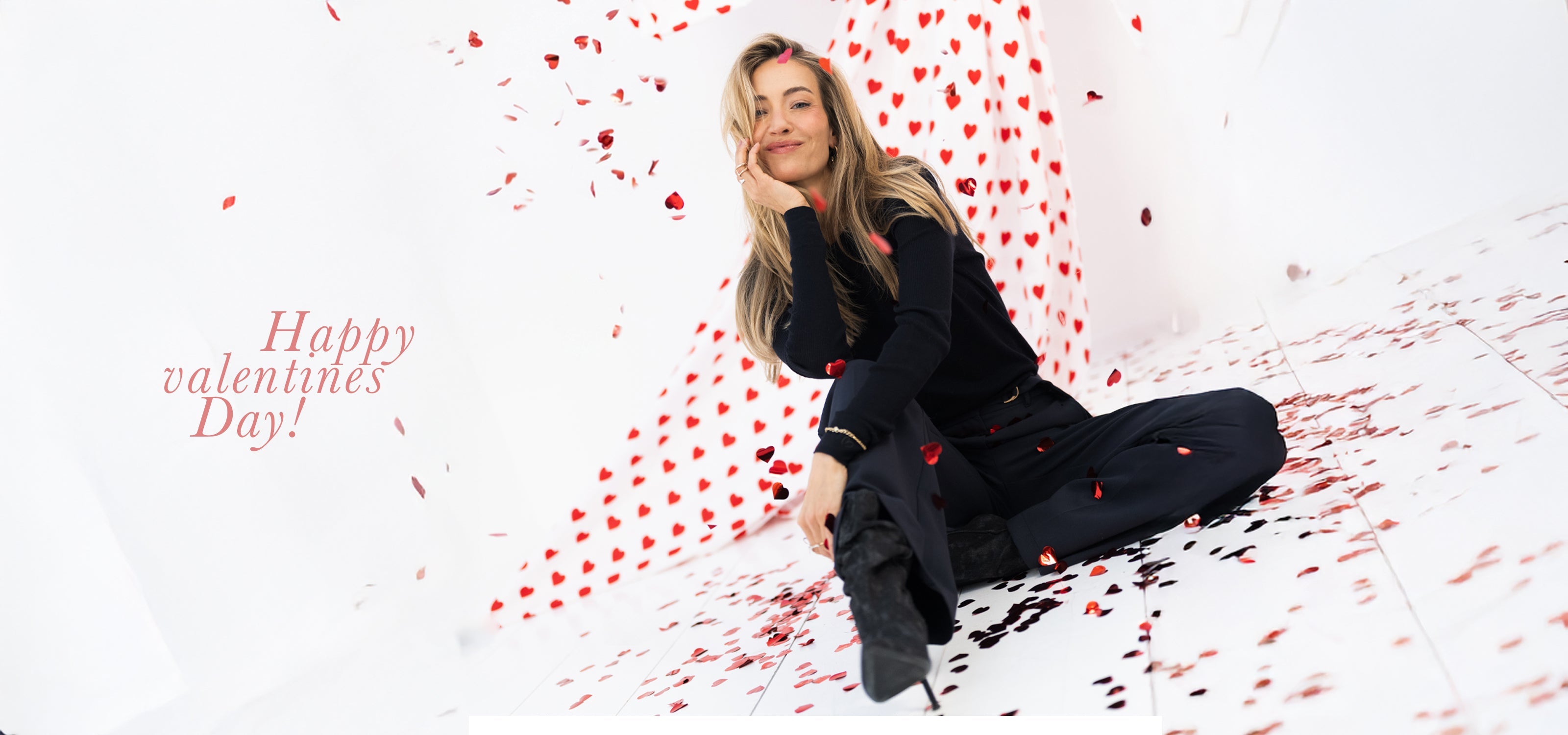 A striped shirt is worn by a woman sitting by a sunlit window, eyes closed and smiling gently. White curtains and natural light create a serene, relaxed atmosphere.
