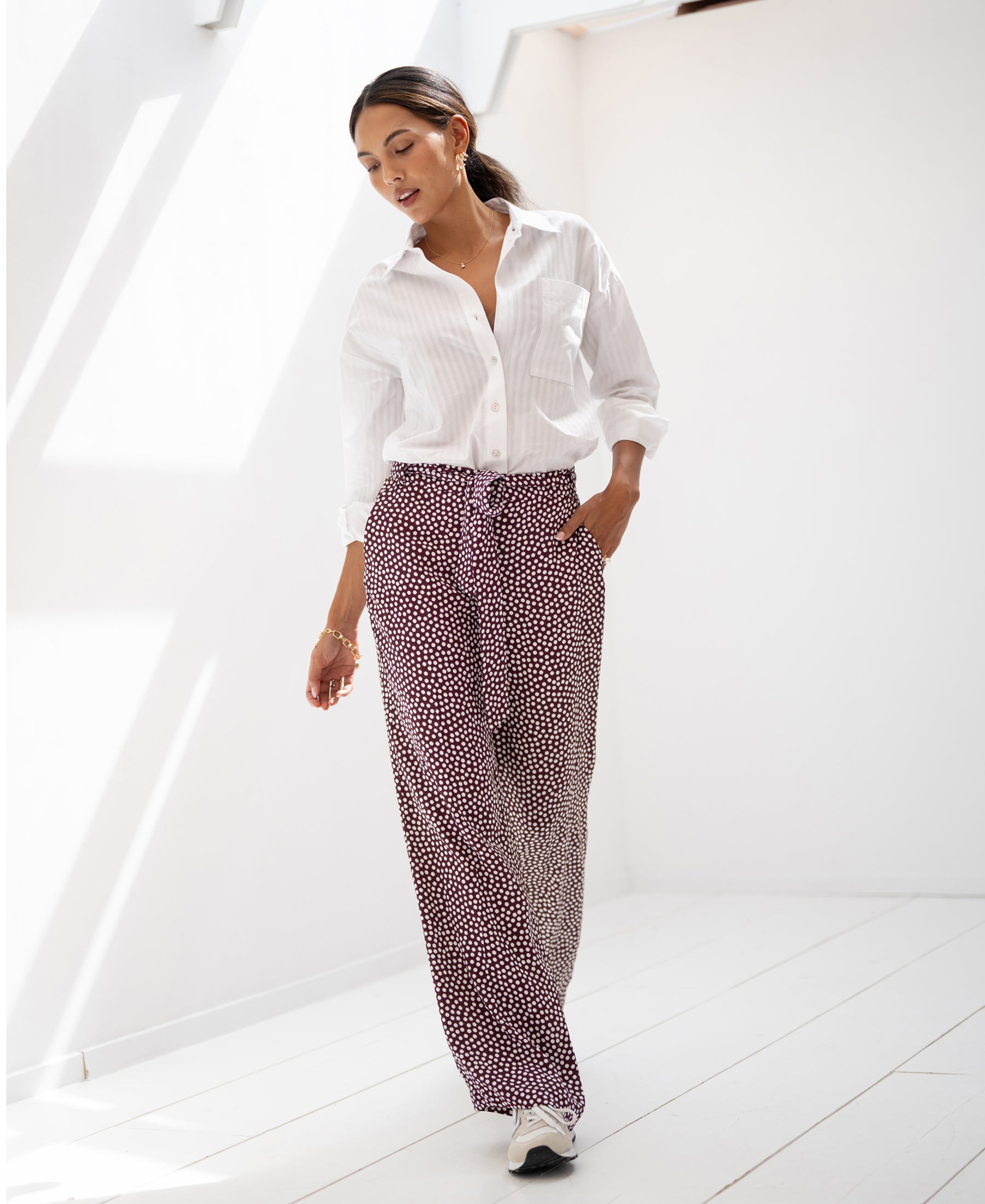White LES ANDELYS wine-ivory polka dot trousers from PLEIN PUBLIQUE shown in a sunlit, minimal room.