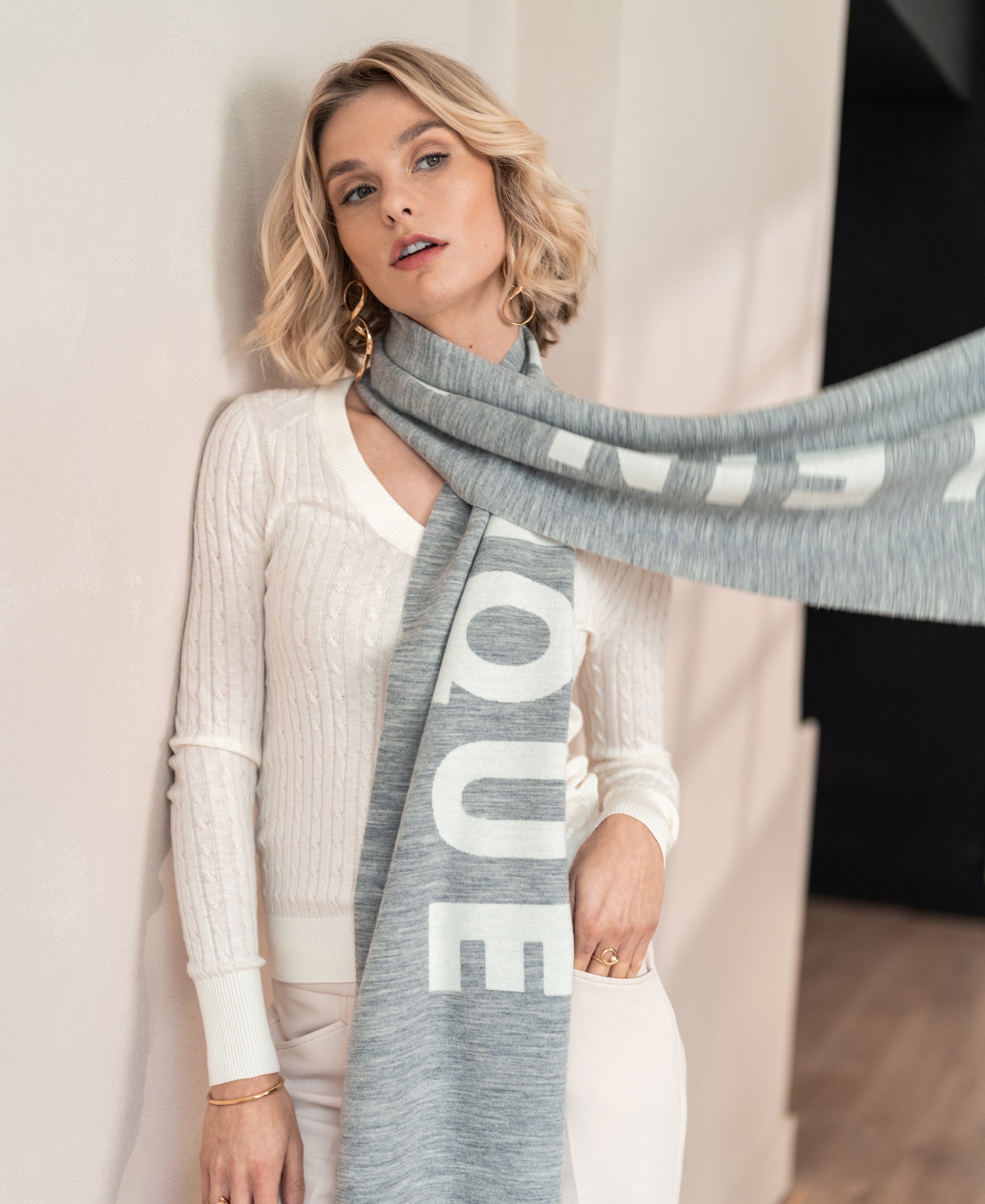 Light grey-ivory wool scarf from SALE's LA BEAU collection, shown indoors.