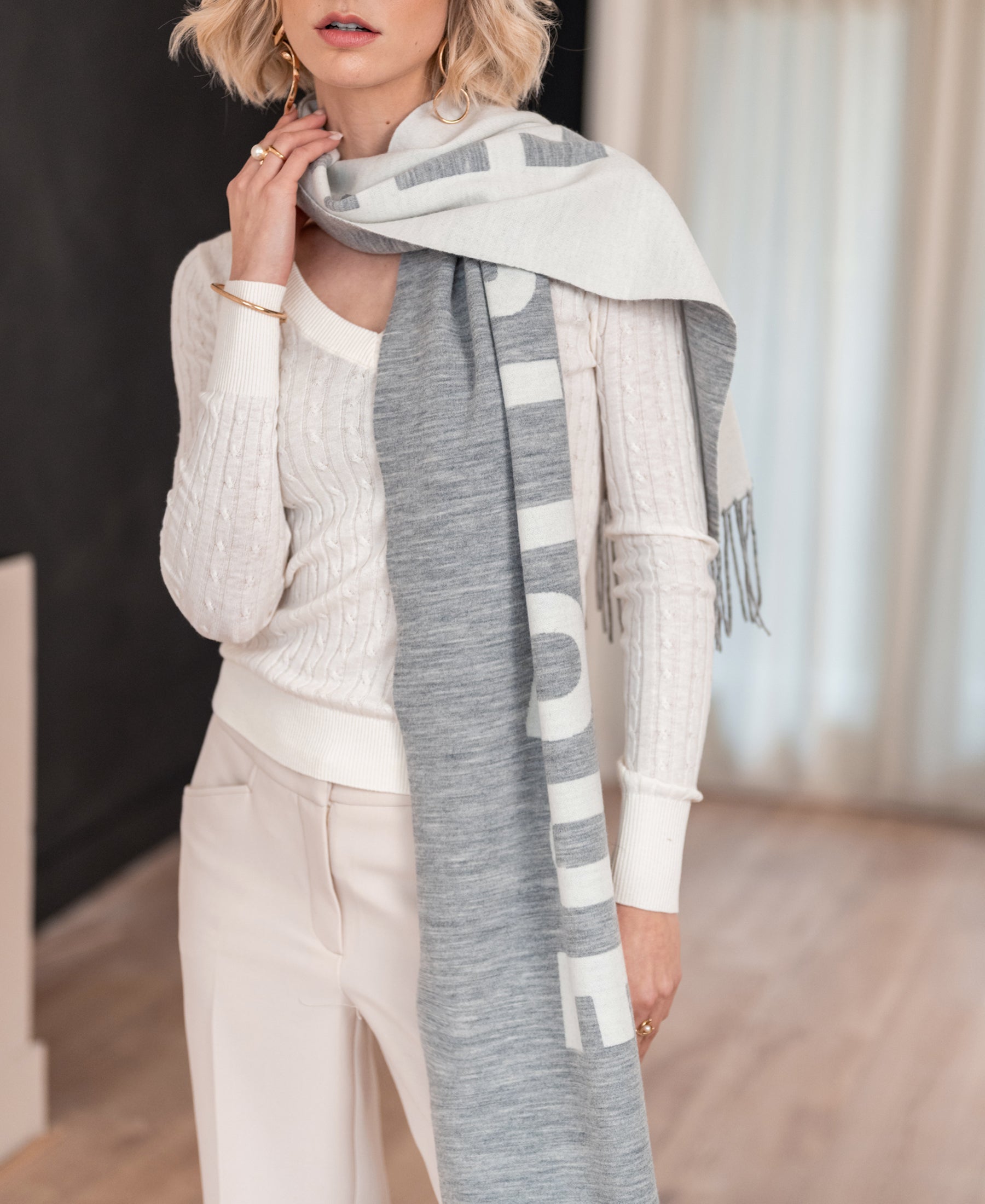 Light gray and ivory wool scarf displayed indoors on light wood floors.