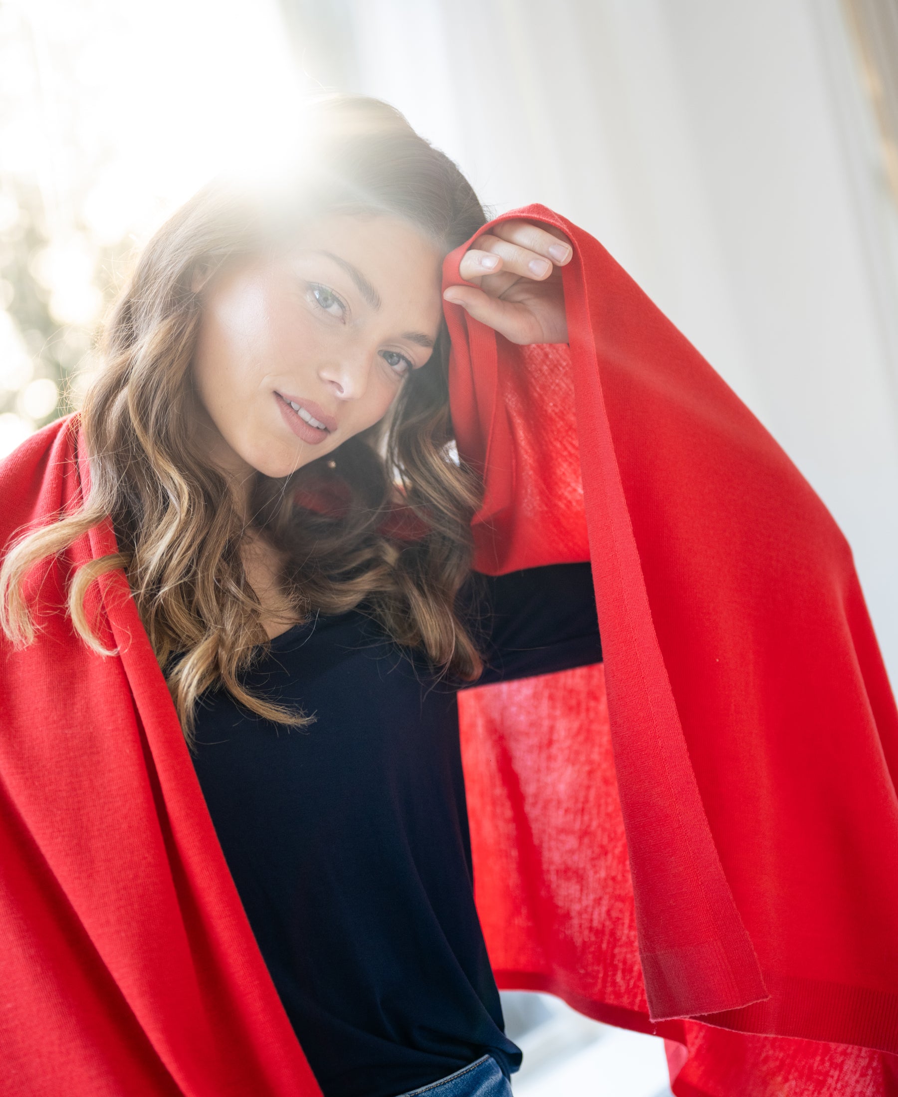 Coral red PLEIN PUBLIQUE Merino wool wrap La Bella shown indoors in sunlight.