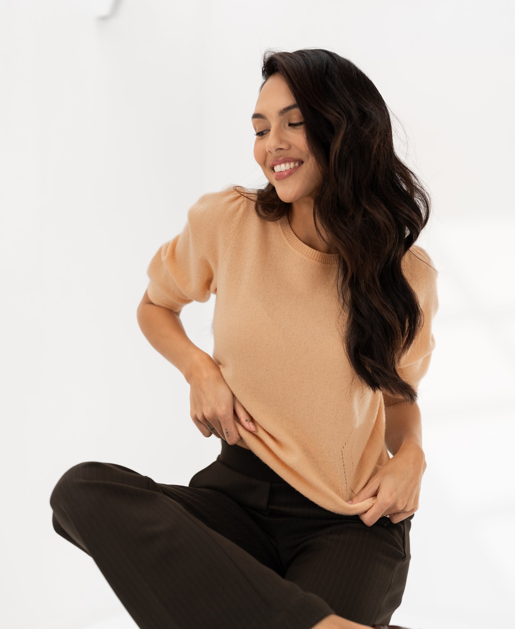 Soft salmon knit sweater shown in a bright, minimal space.