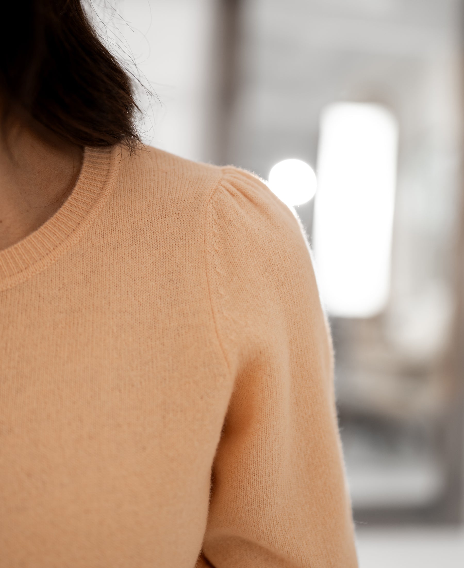 Close-up of the PLEIN PUBLIQUE LA BLANCHE Sweater in Soft Salmon with short sleeves, partial view, face partially out of frame.
