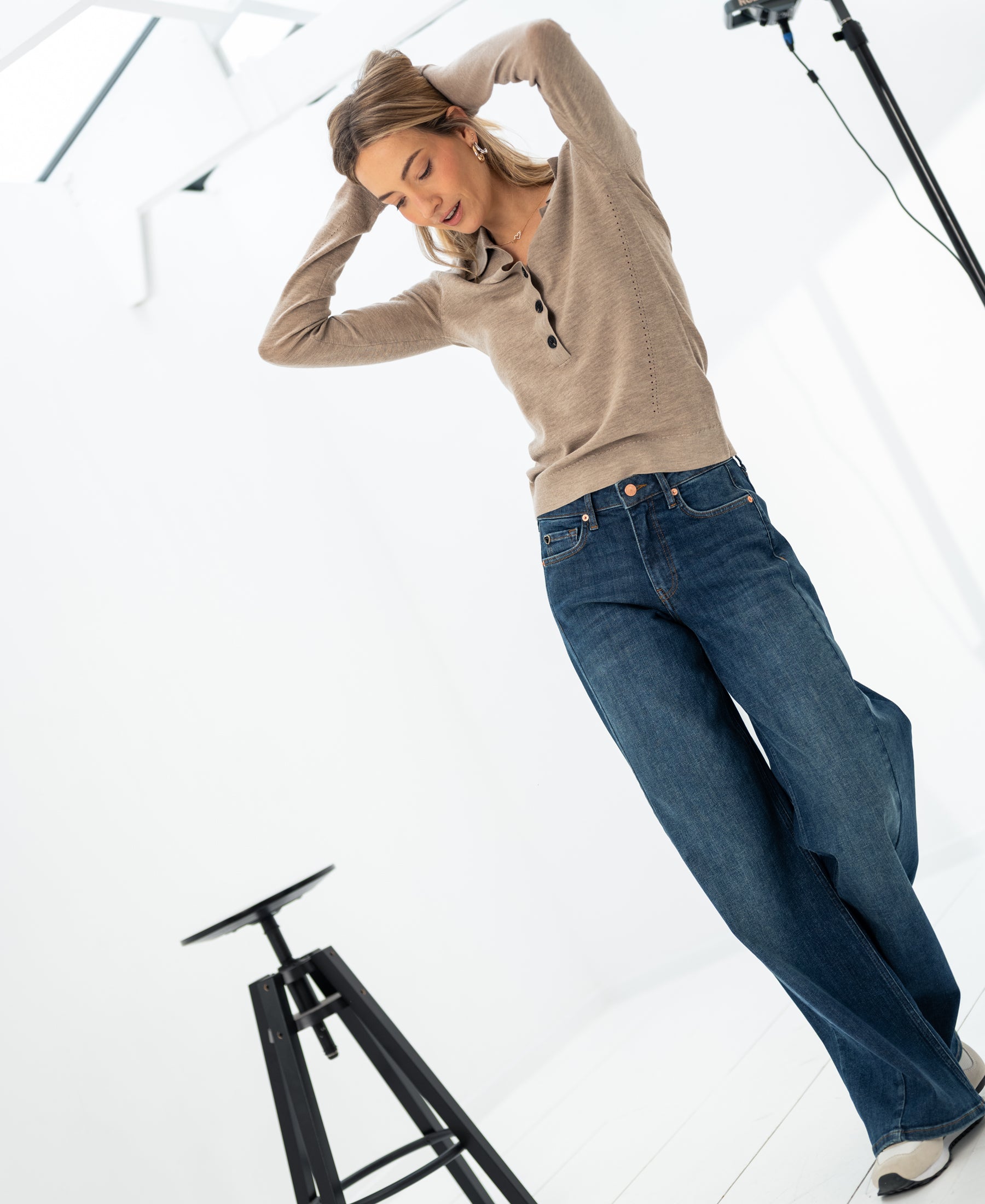 Woman wearing the Merino wool polo shirt LE BOBIGNY Sand mélange by PLEIN PUBLIQUE in a bright studio.