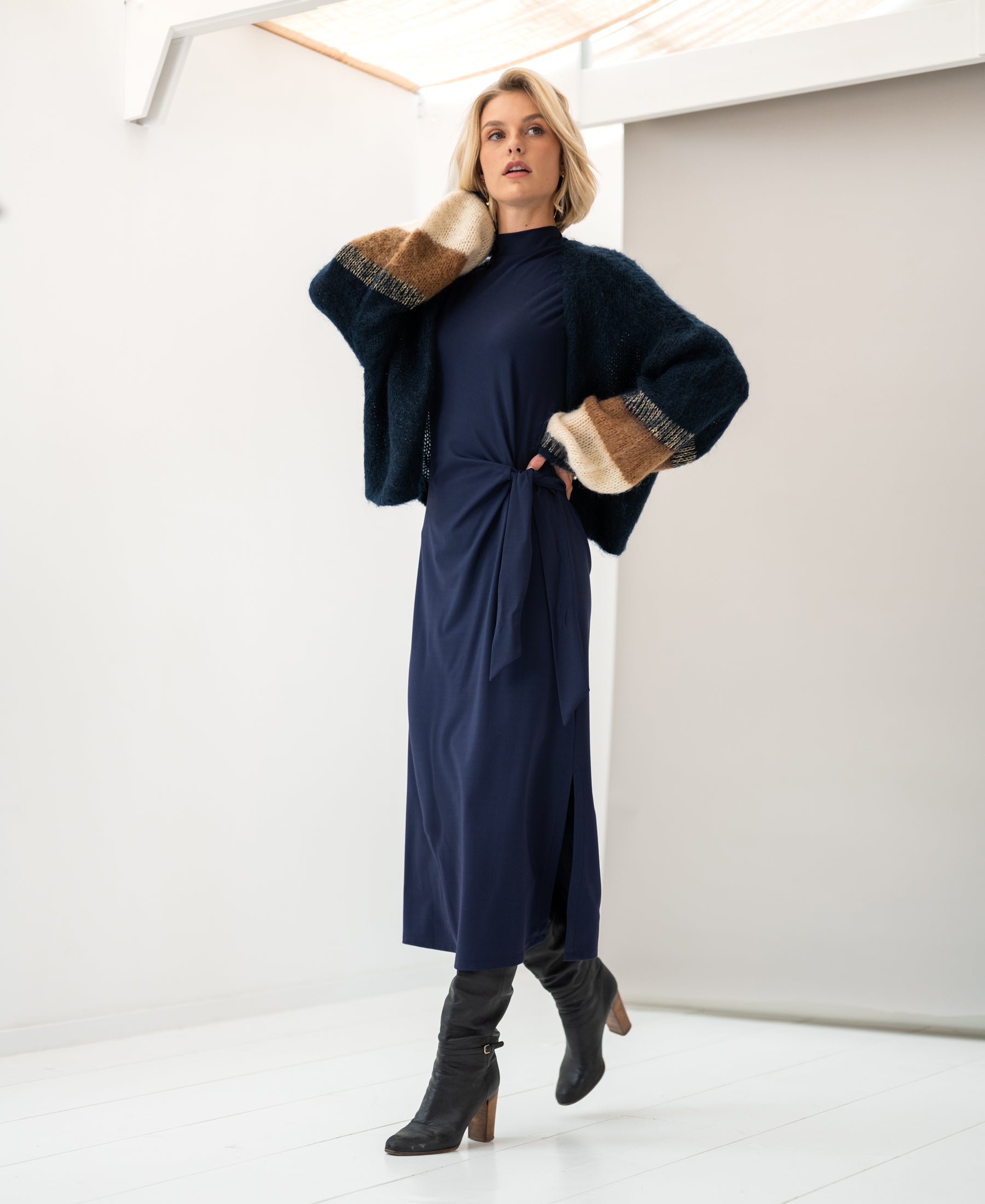 A woman poses indoors in a PLEIN PUBLIQUE Toulouse dark blue travel dress.