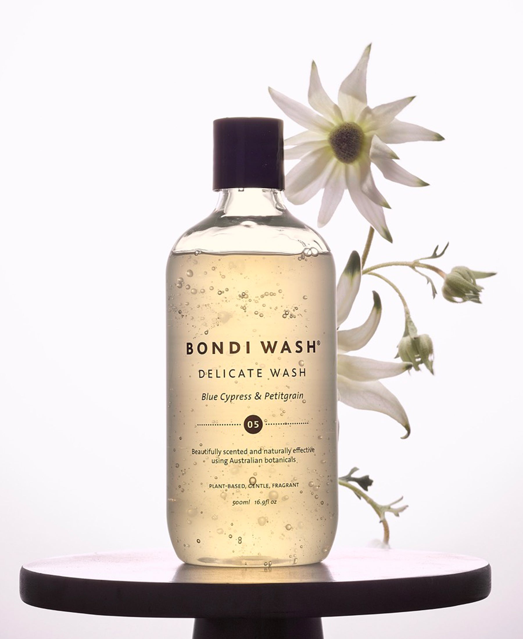 A bottle of Plein Publique delicate laundry detergent Bondi Wash Blue Cypress & Petitgrain on a table.