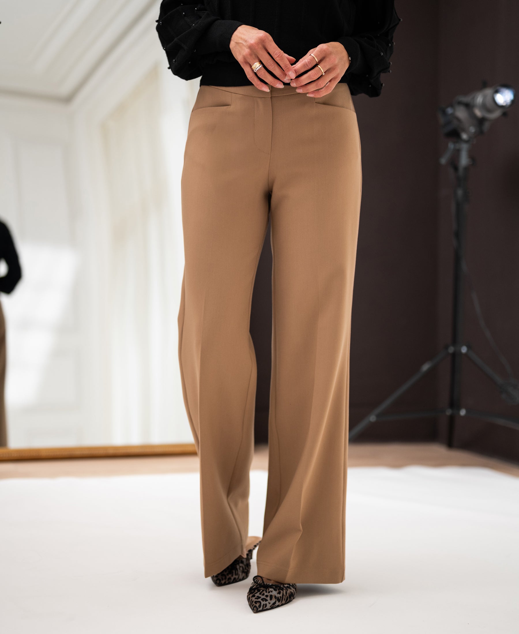 Wide-leg camel trousers in English translation, shown indoors.