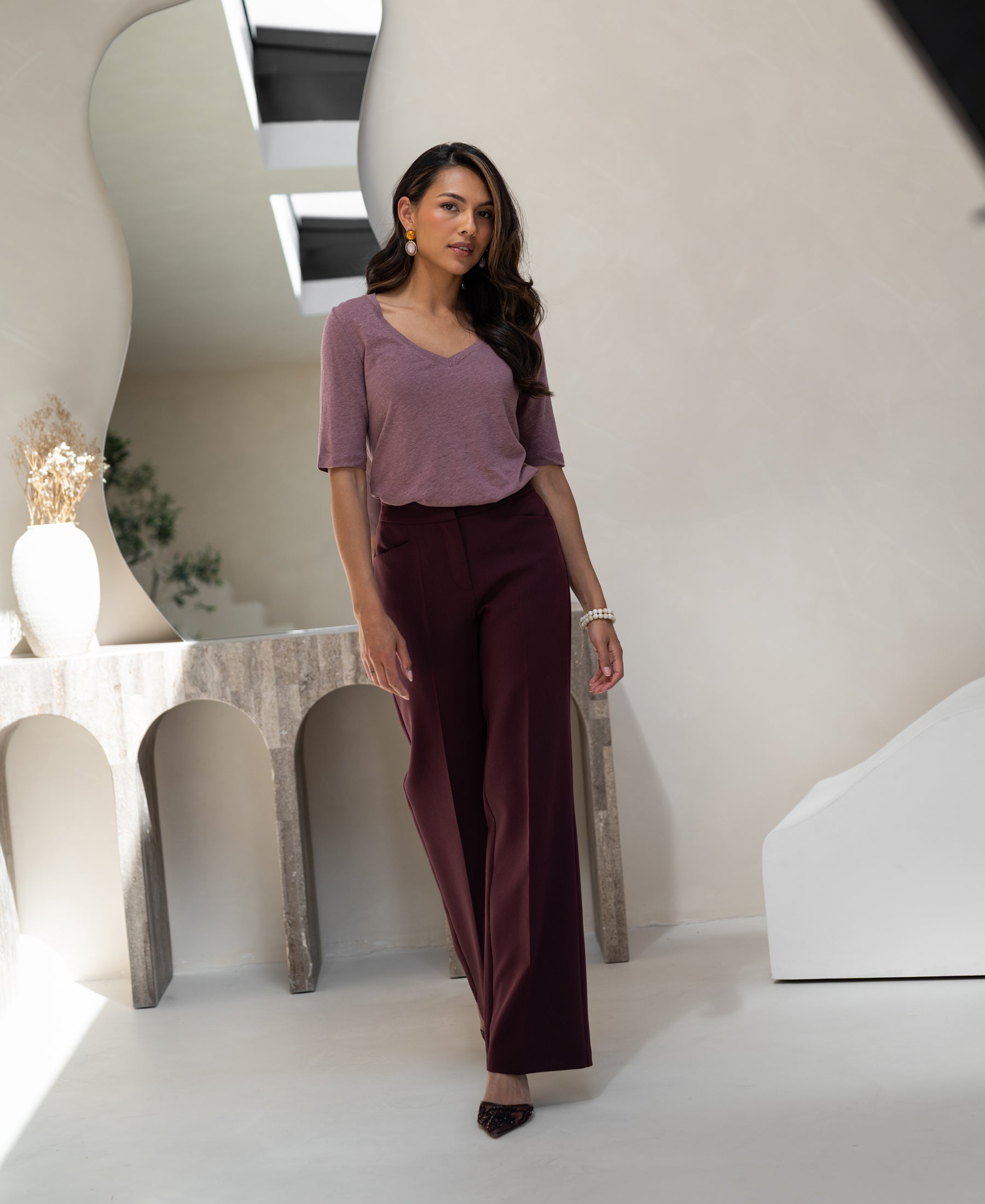 Woman wears mauve linen T-shirt in a modern, stylishly decorated room.