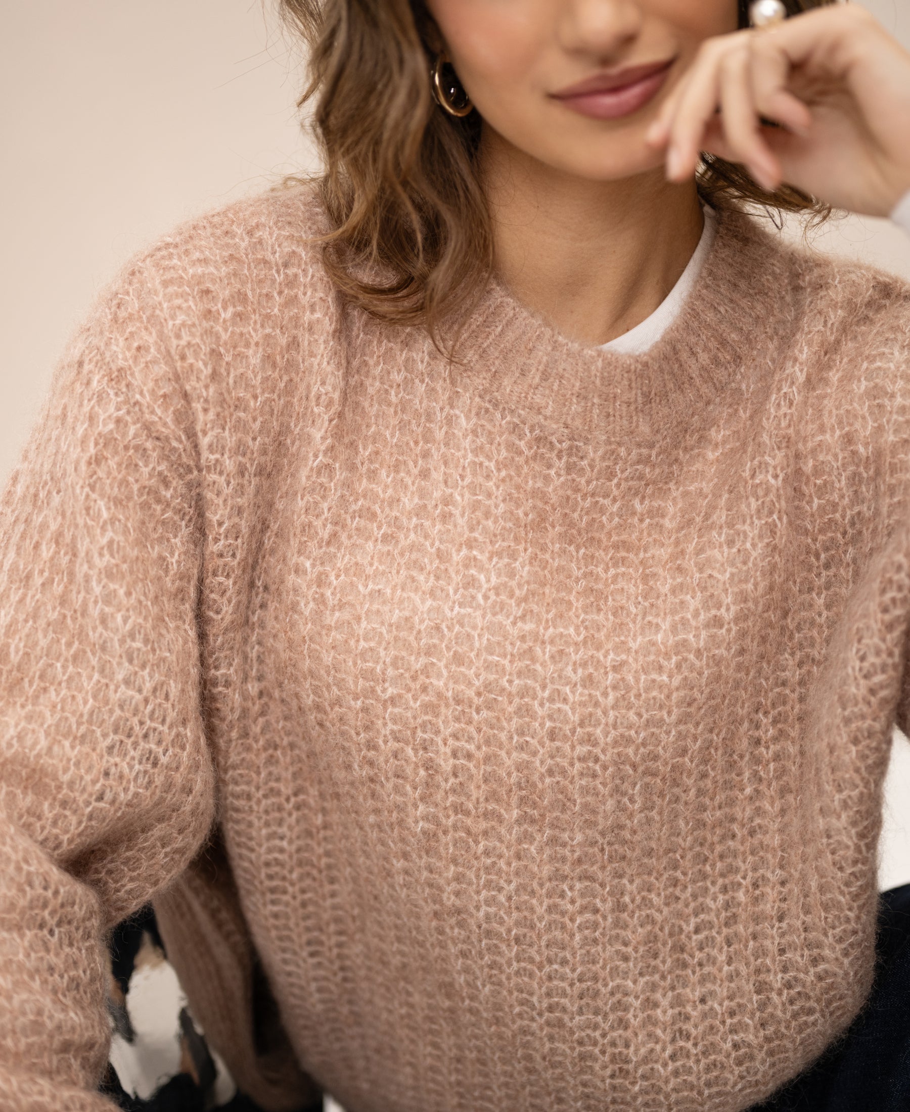 Light brown mohair sweater by PLEIN PUBLIQUE, shown on a model with hand near her face.