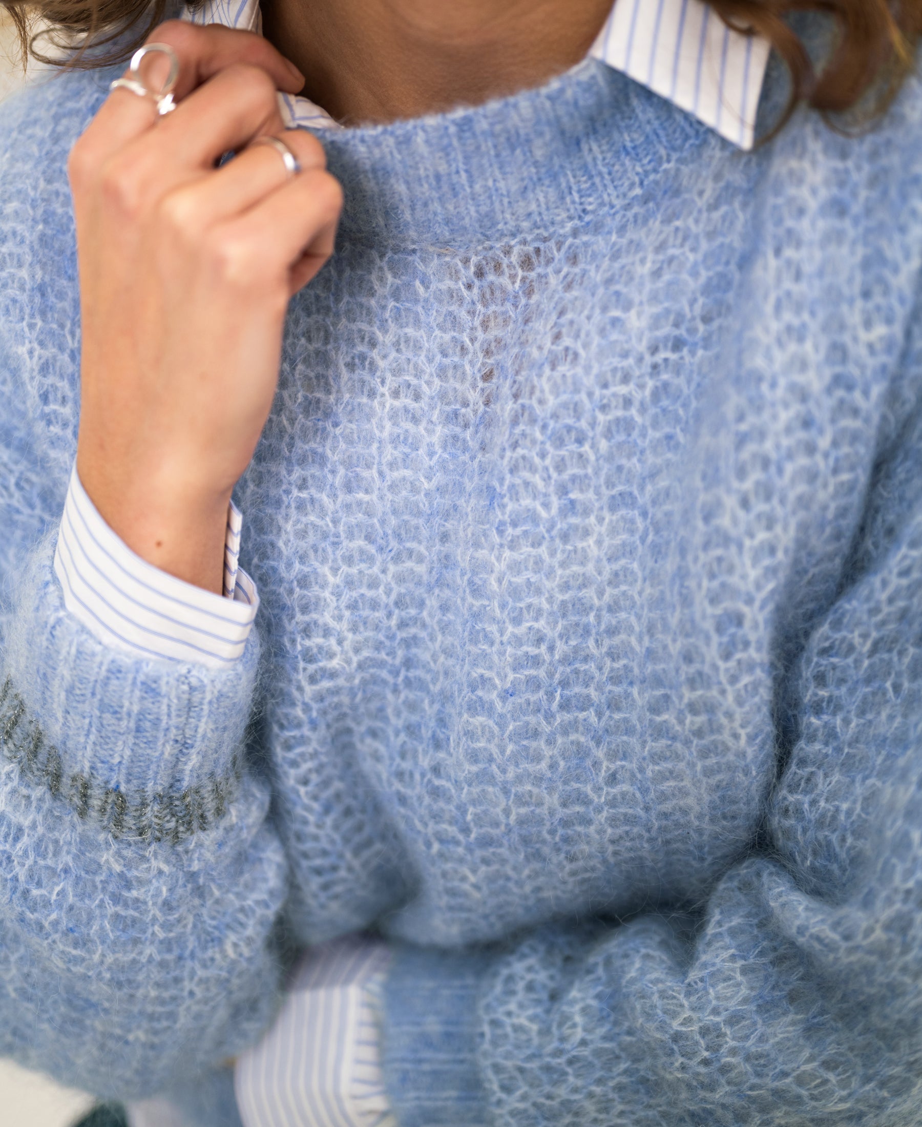 Person wearing a light blue mohair sweater, holding the collar.