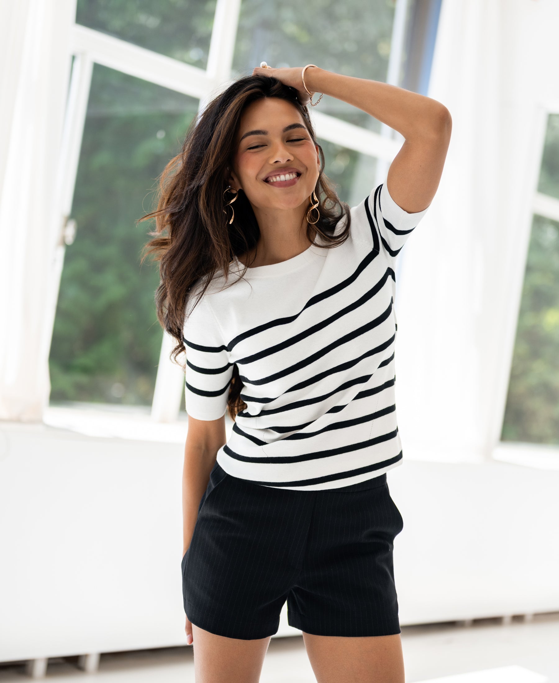 Ivory and black Breton sweater by PLEIN PUBLIQUE shown in a bright room with large windows.