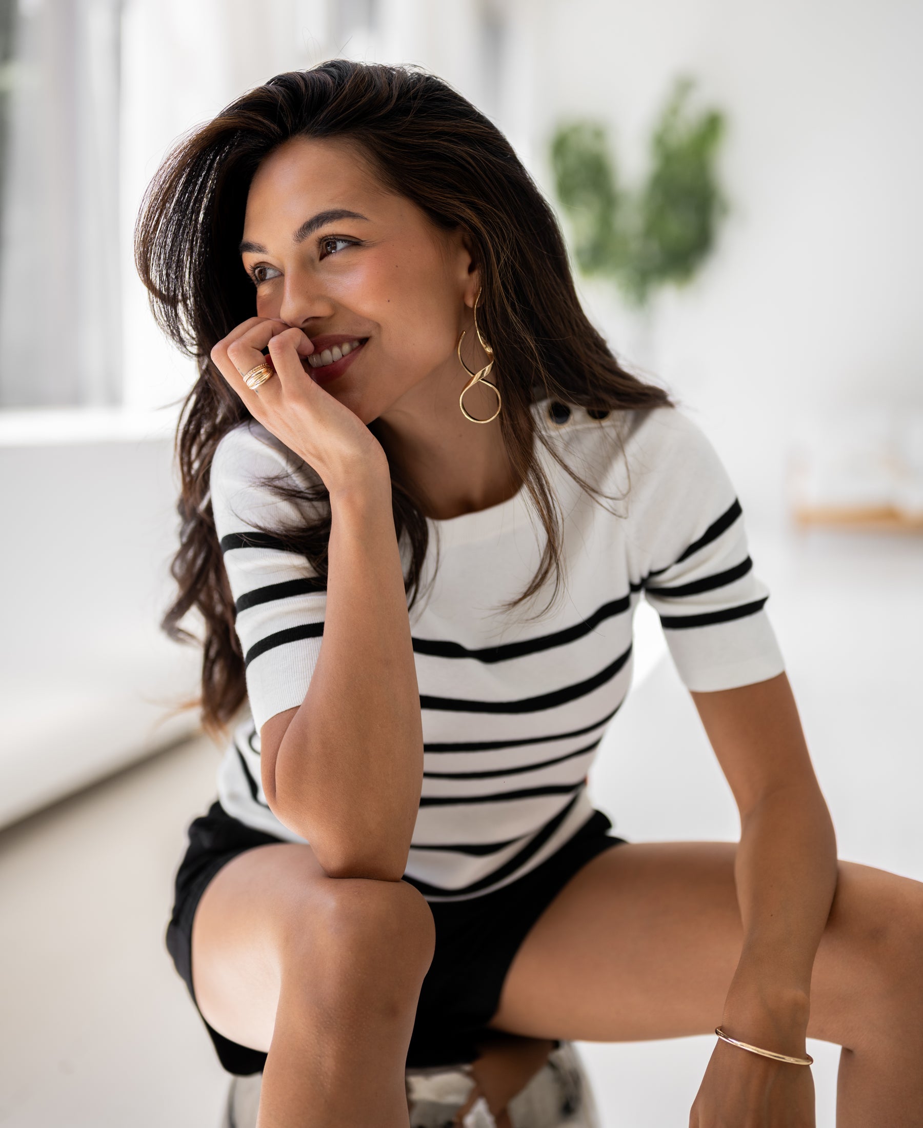 Ivory-black striped knit sweater in a Breton style, shown indoors against a blurred background.