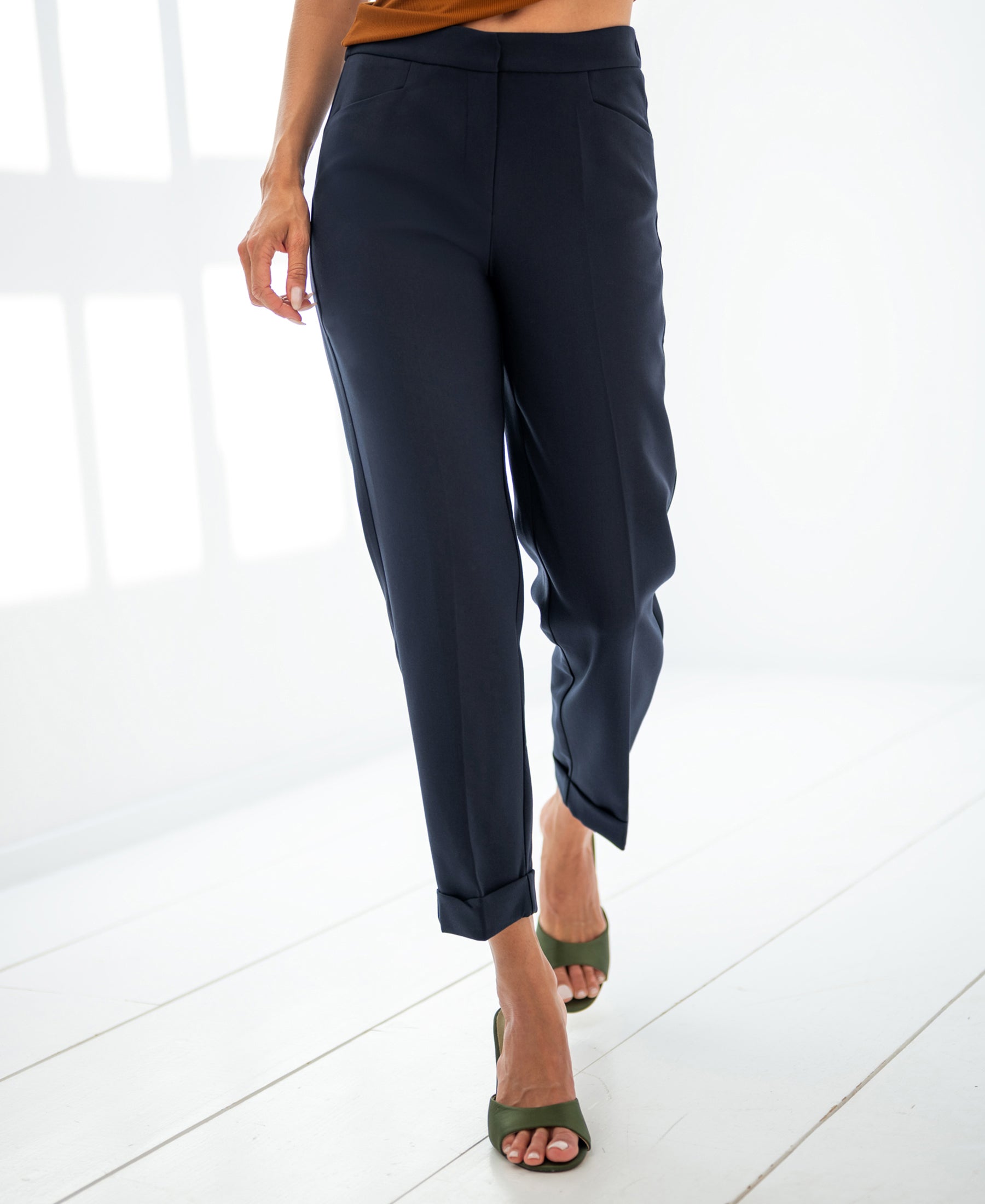 Woman wearing navy blue PLEIN PUBLIQUE LE FAUBOURG 7/8 trousers, standing indoors on a white wooden floor.