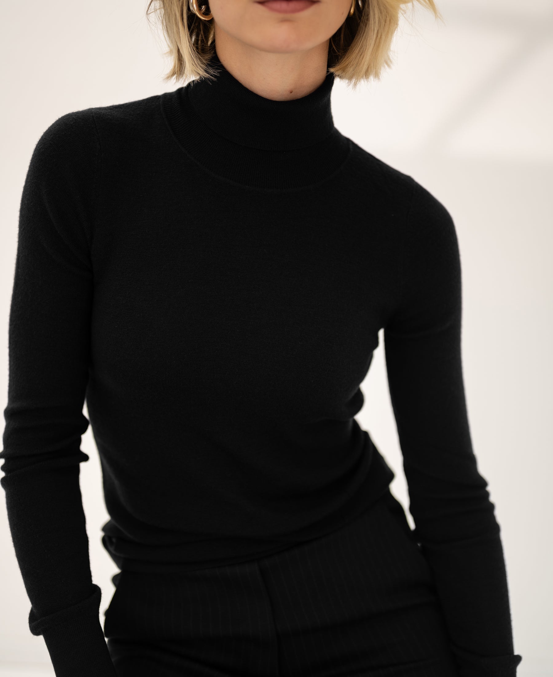 Black PLEIN PUBLIQUE Merino wool turtleneck sweater LA FORTE, worn by a woman, shown on a light background.