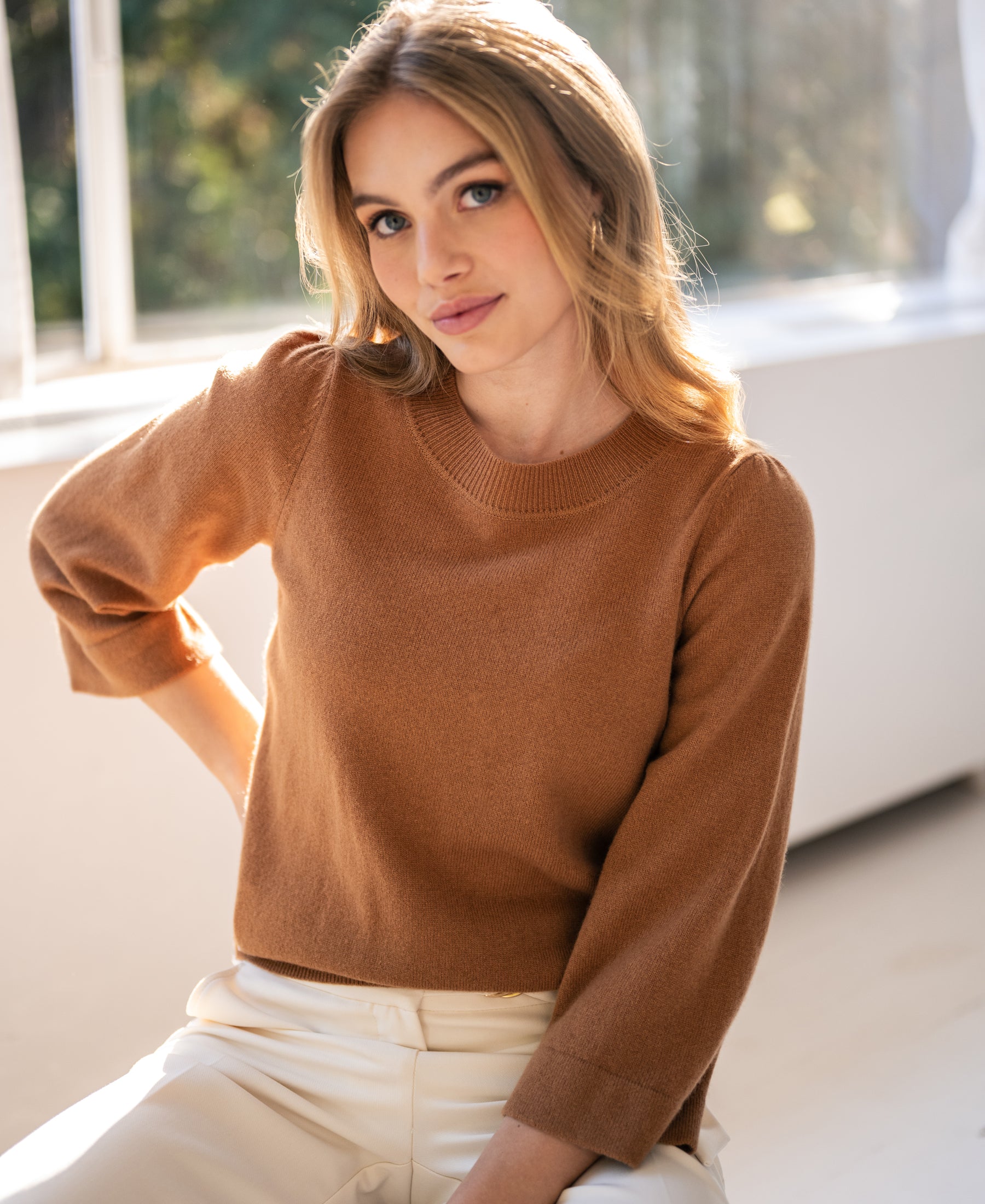 Camel-colored LE FREJUS merino wool sweater by PLEIN PUBLIQUE, shown indoors in sunlight.