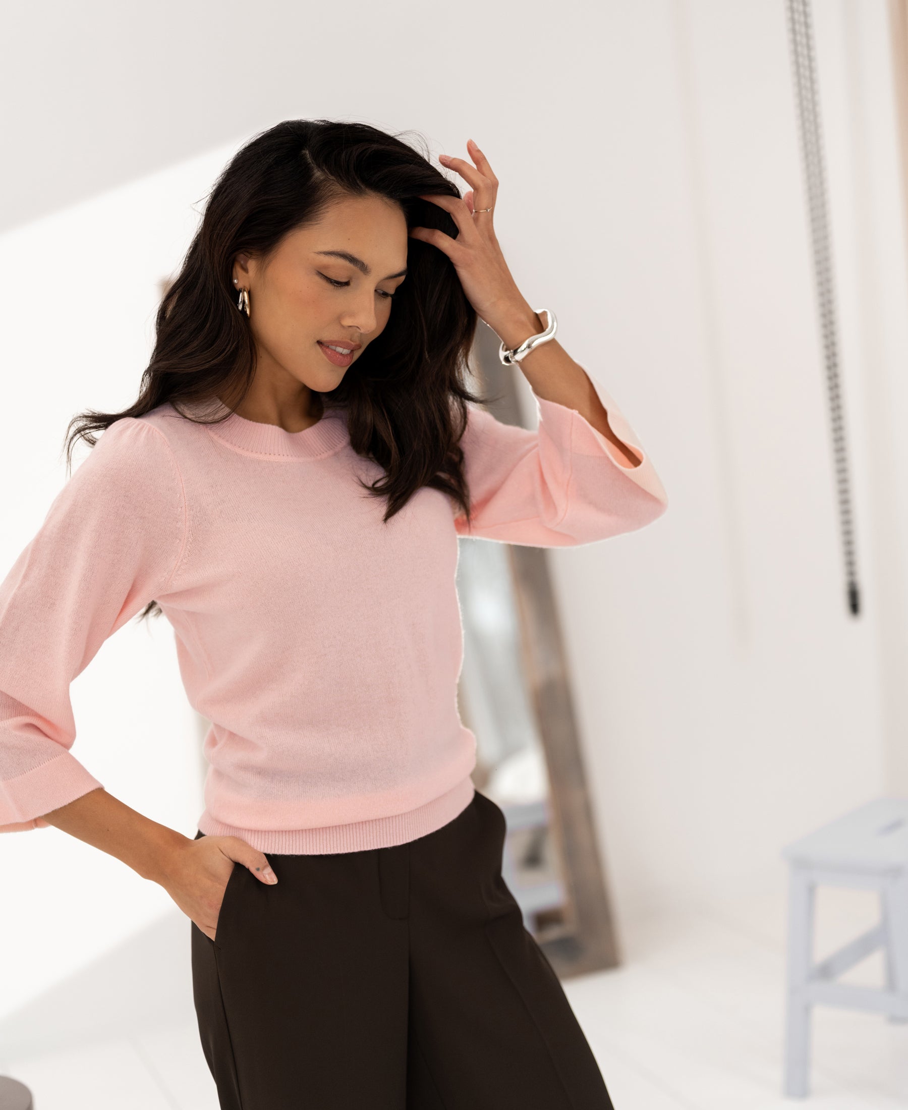 Woman wearing the LE FREJUS Merino wool sweater by PLEIN PUBLIQUE in a light, minimalist room.