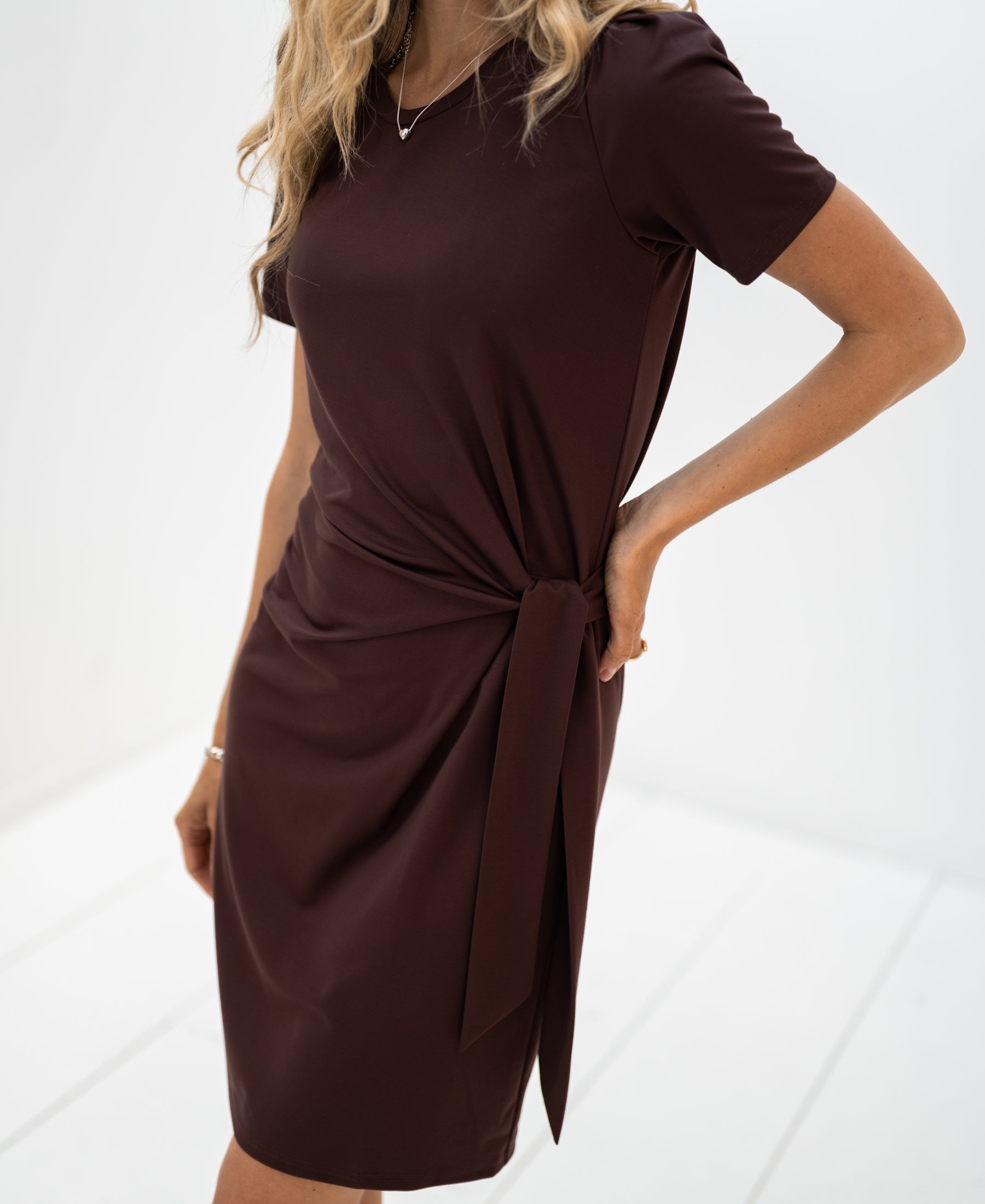 Short-sleeved, knee-length tie-front dress in cacao color, shown in a bright white room.