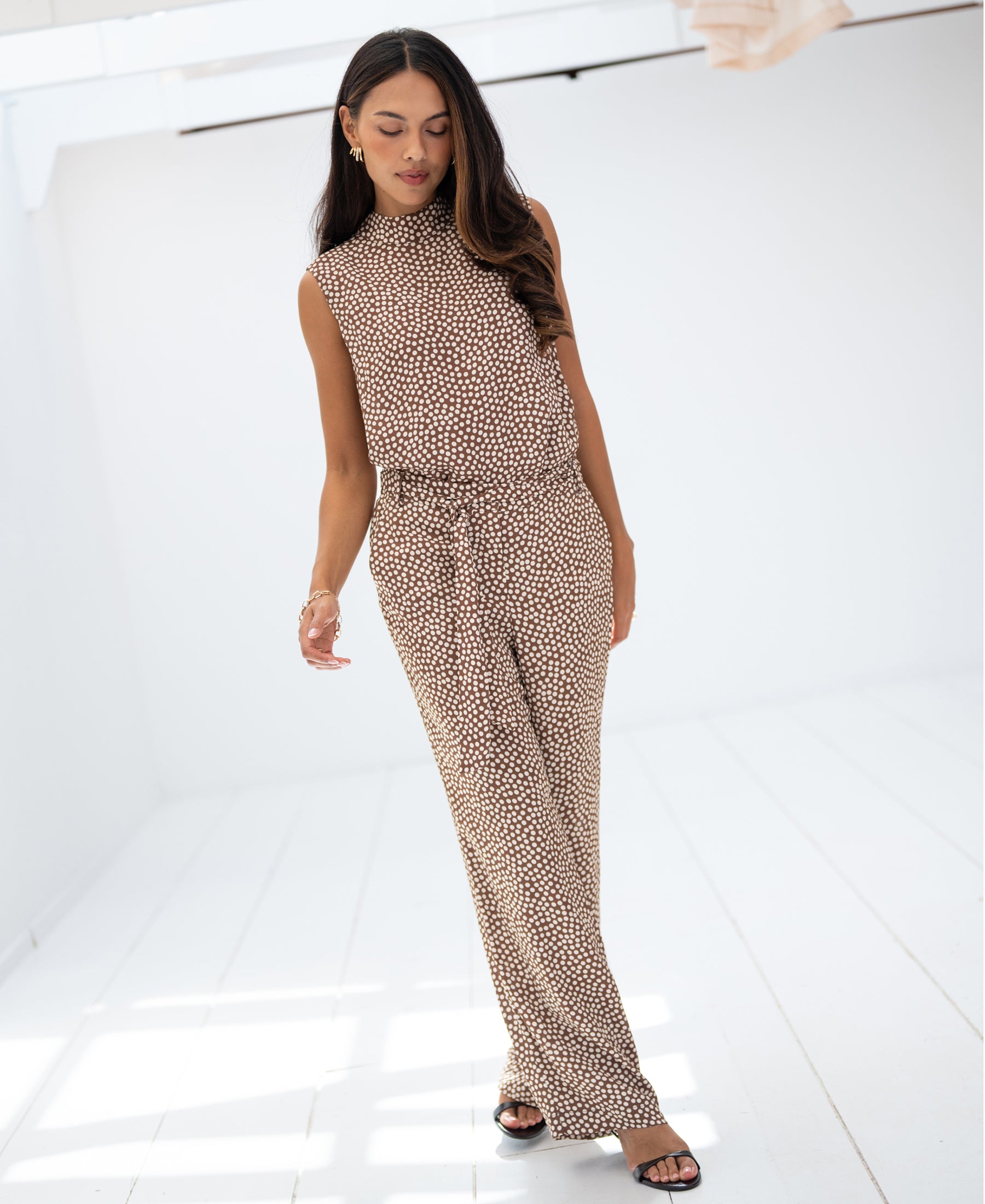 Woman wearing mocha mousse-colored striped top in a bright, minimalist room.
