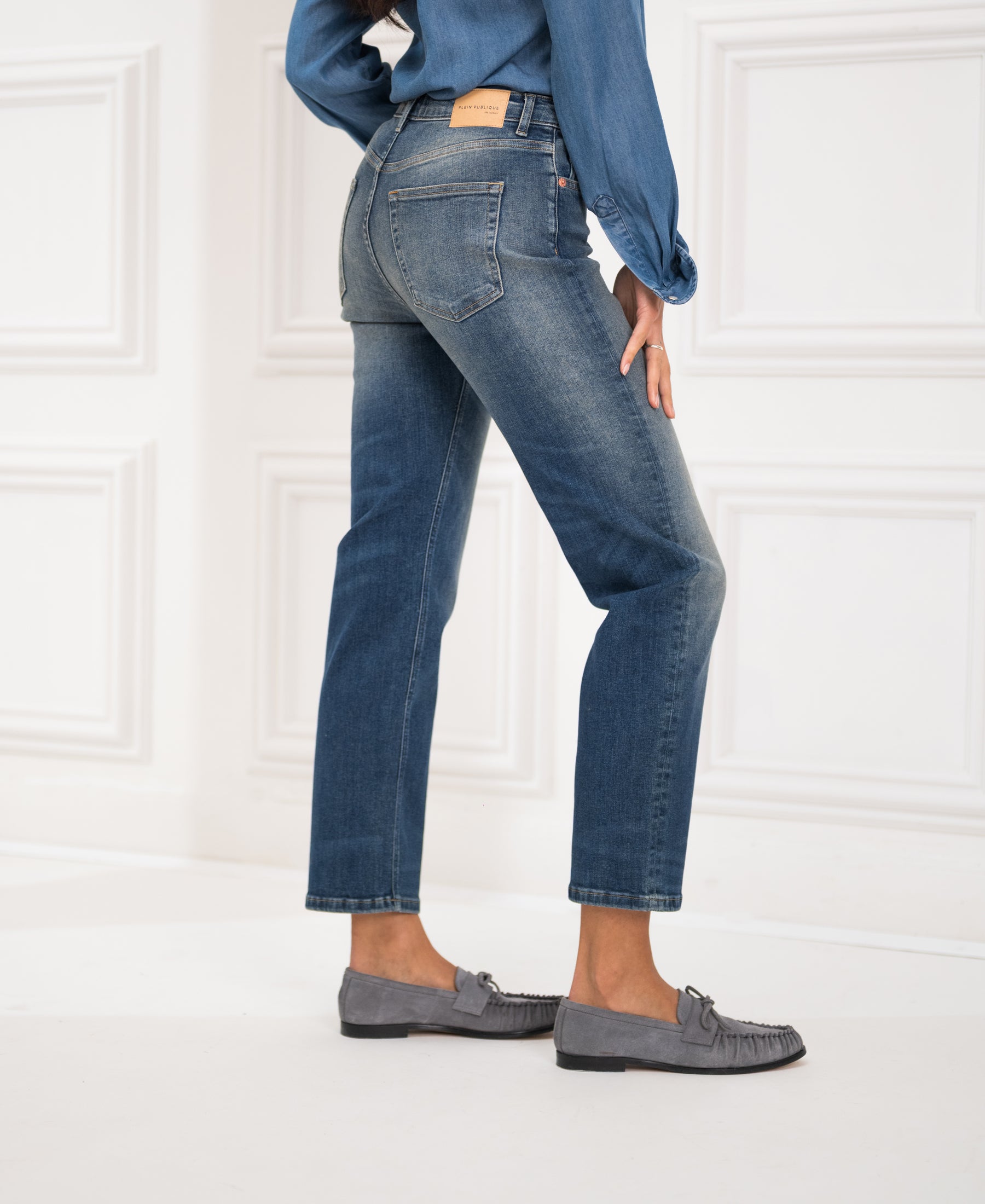 Person wearing blue vintage cropped jeans in a white paneled room.
