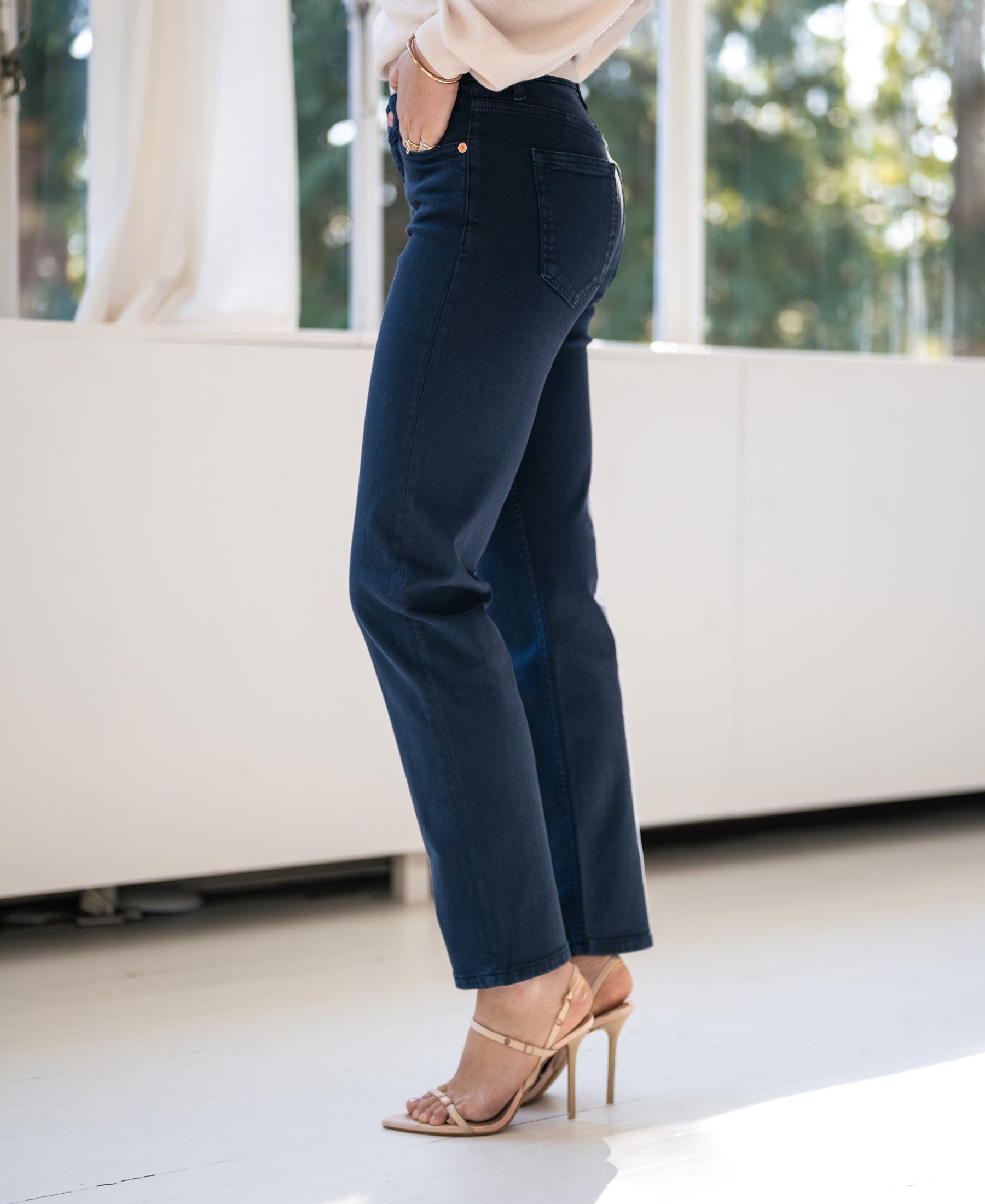 Dark blue PLEIN PUBLIQUE cropped jeans, shown indoors by a sunlit window.
