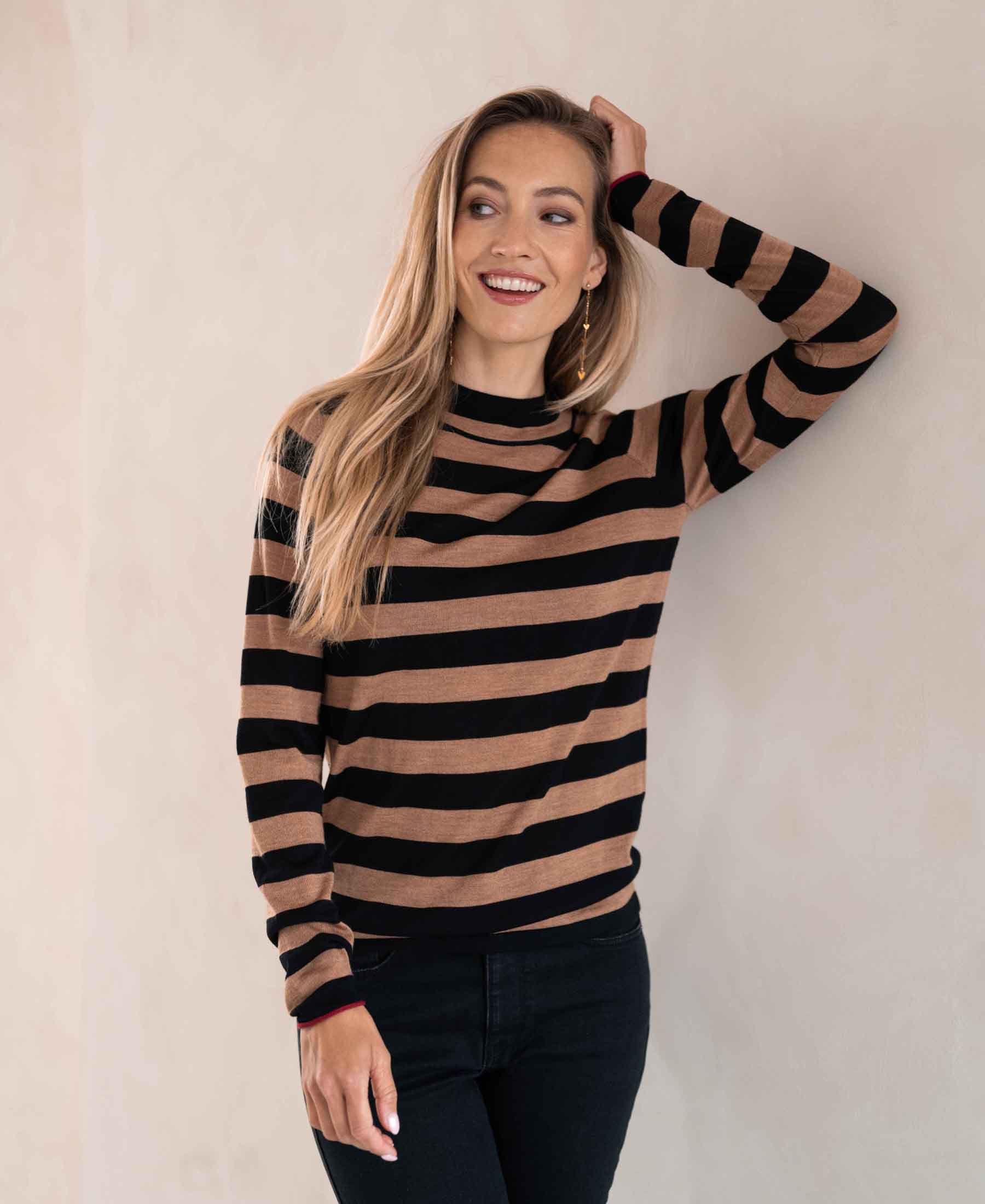 Langharige blonde vrouw draagt LE JEUDI Striped Turtleneck Black-Chai Tea tegen lichte muur.