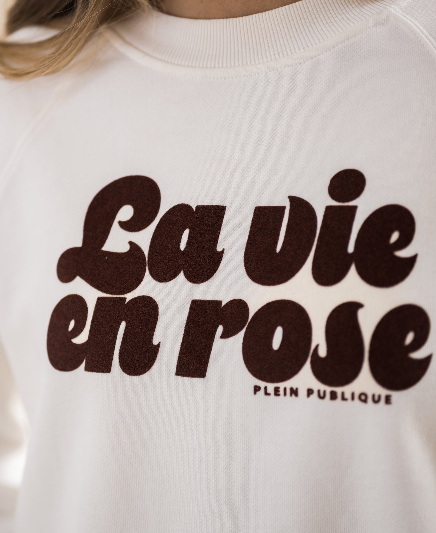 Close-up of PLEIN PUBLIQUE’s LA HARPER sweater in ivory-cocoa with bold brown “La vie en rose” text.