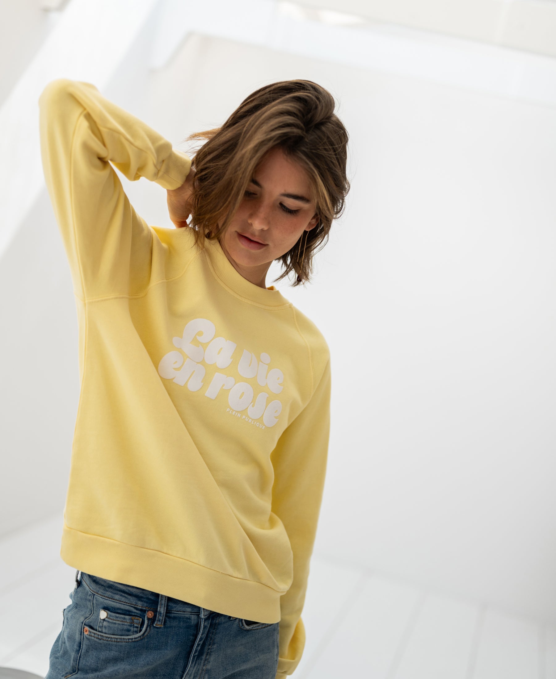 Yellow LA HARPER sweater by LA VIE from PLEIN PUBLIQUE displayed in a bright, minimalist room.