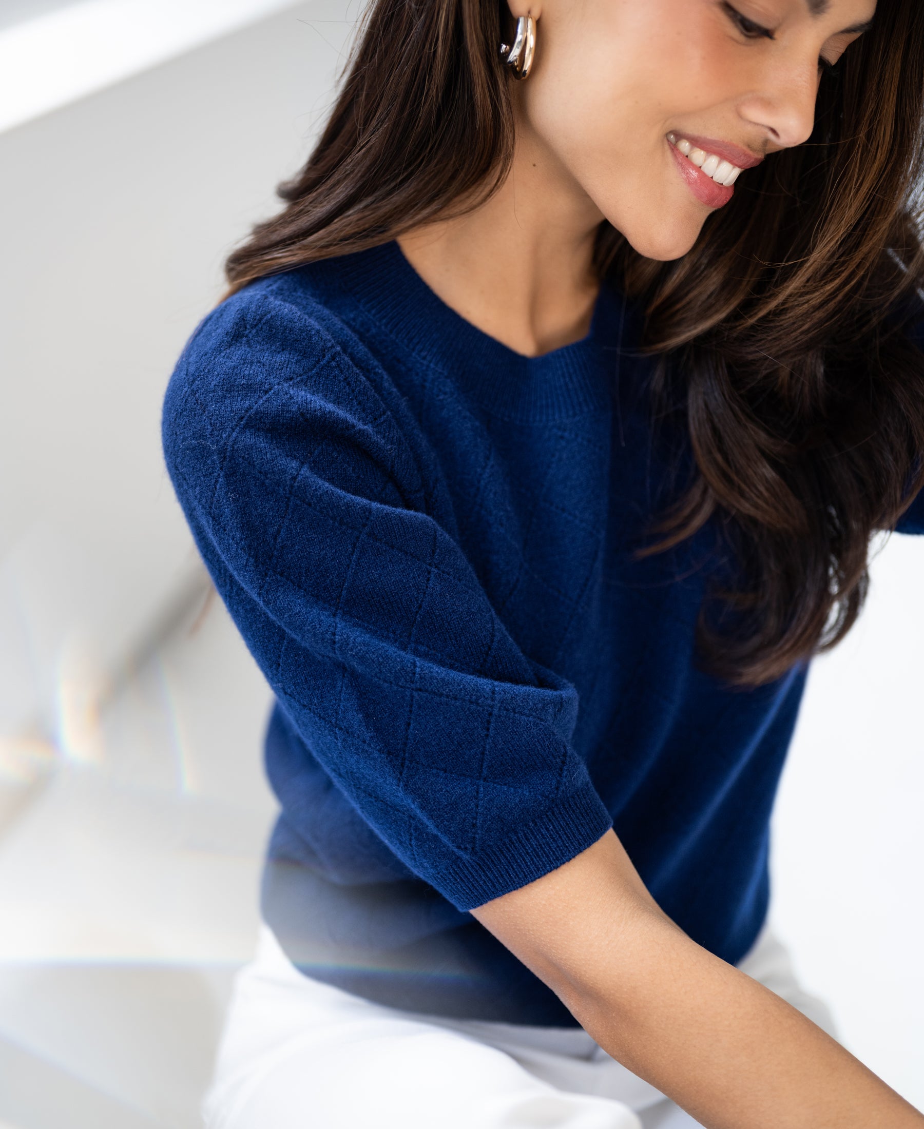 Navy argyle merino wool sweater with LE HARVARD design, shown in a bright, minimalist space.