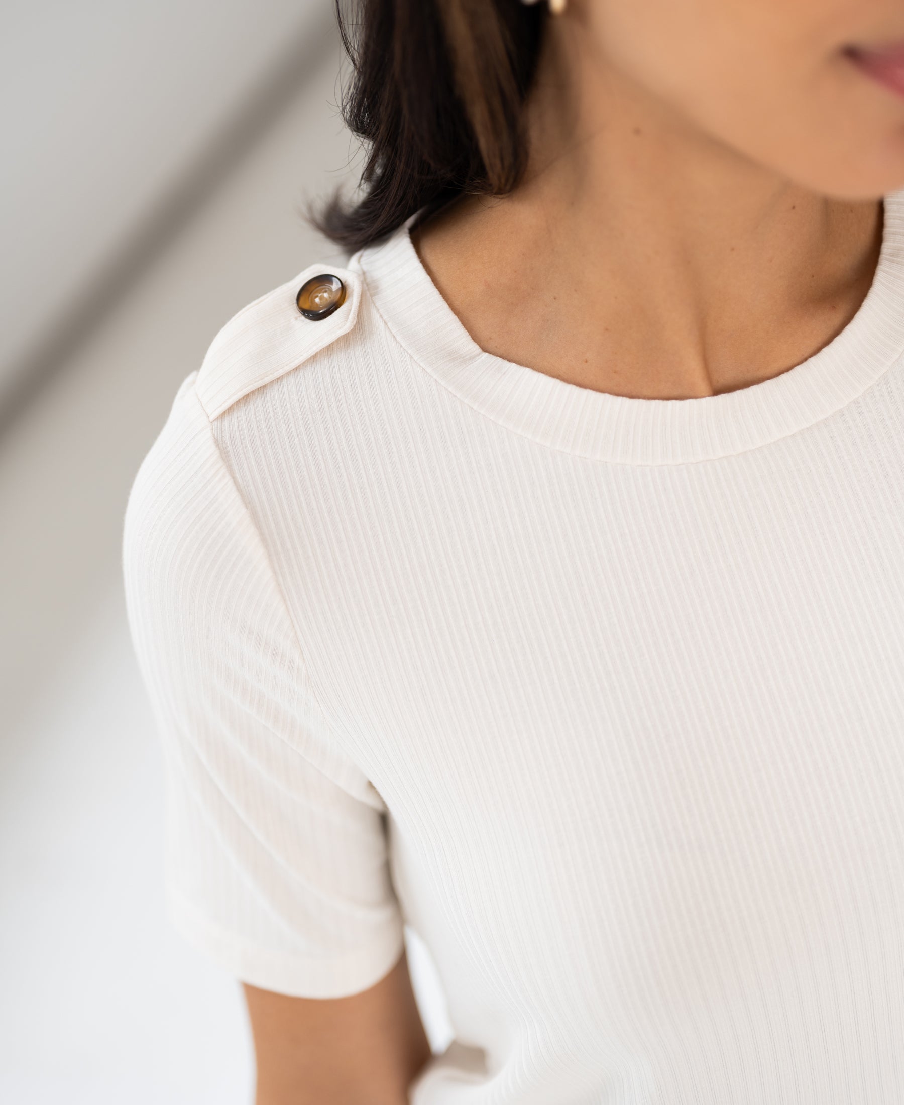 Cream bamboo T-shirt with shoulder button detail, shown from neck to mid-arm.