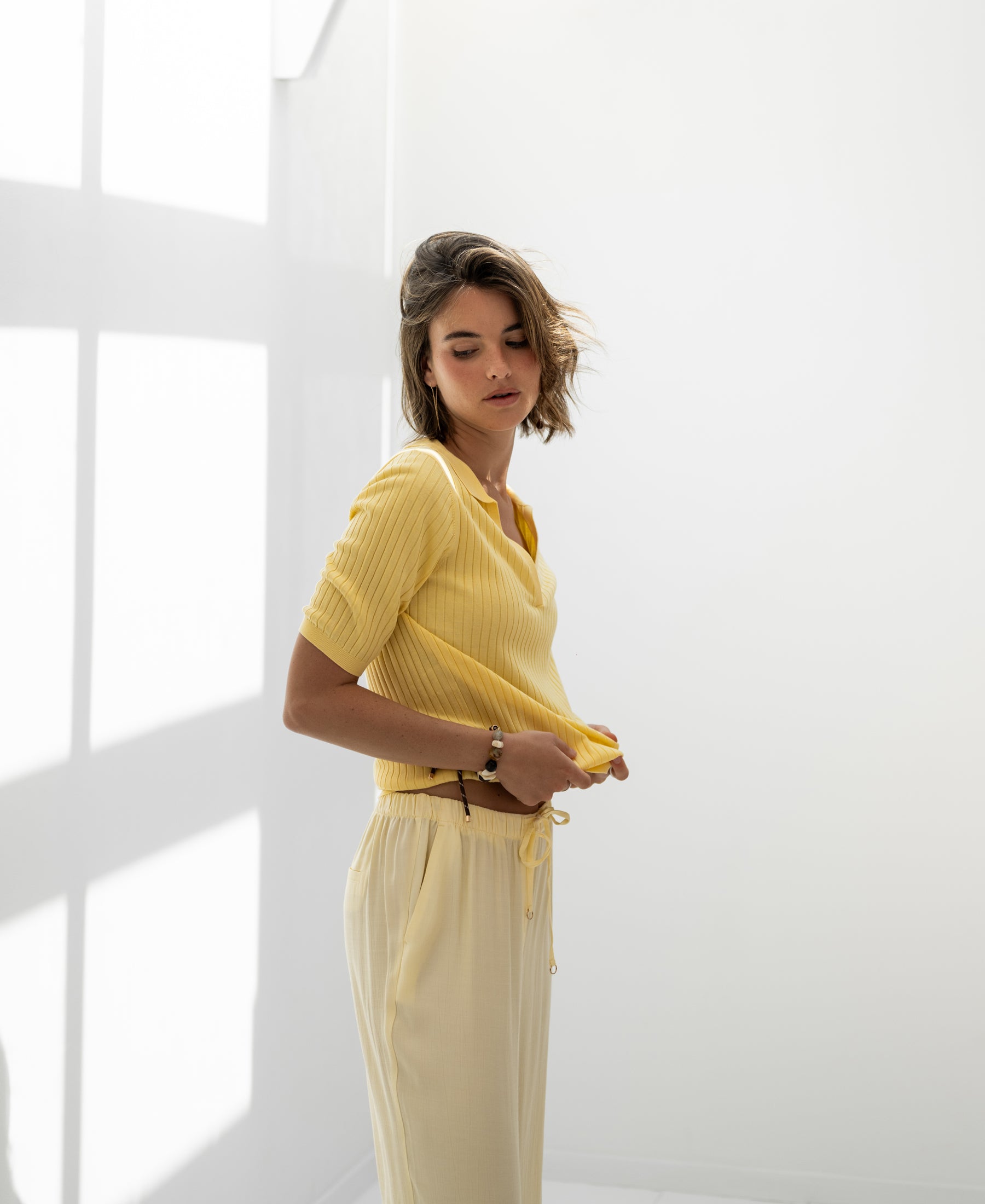 Yellow Tencel-silk polo shirt by Plein Publique in sunlight with shadows cast in a bright room.