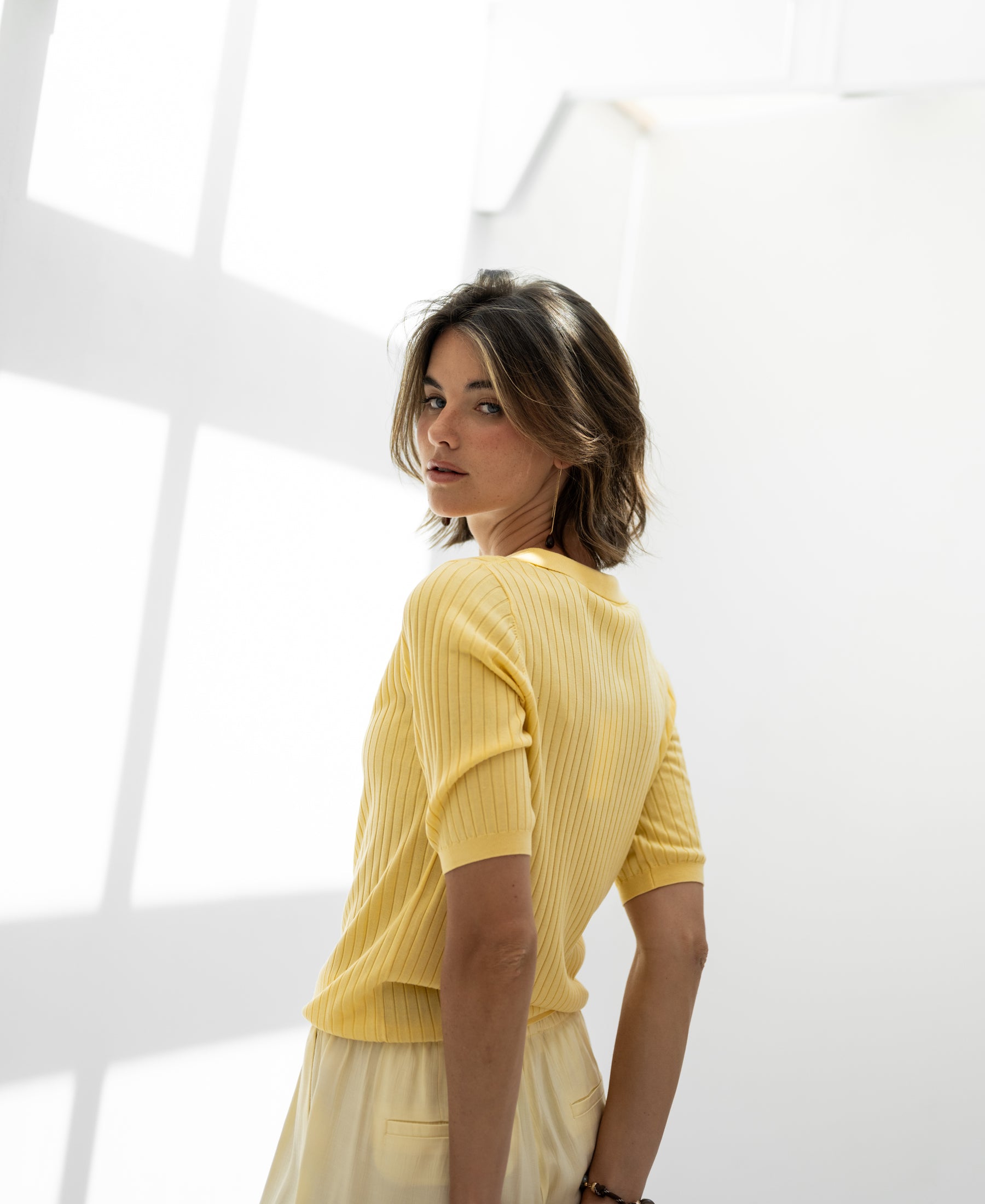 Yellow Tencel-silk polo shirt by PLEIN PUBLIQUE shown in sunlight, back and shoulder view.