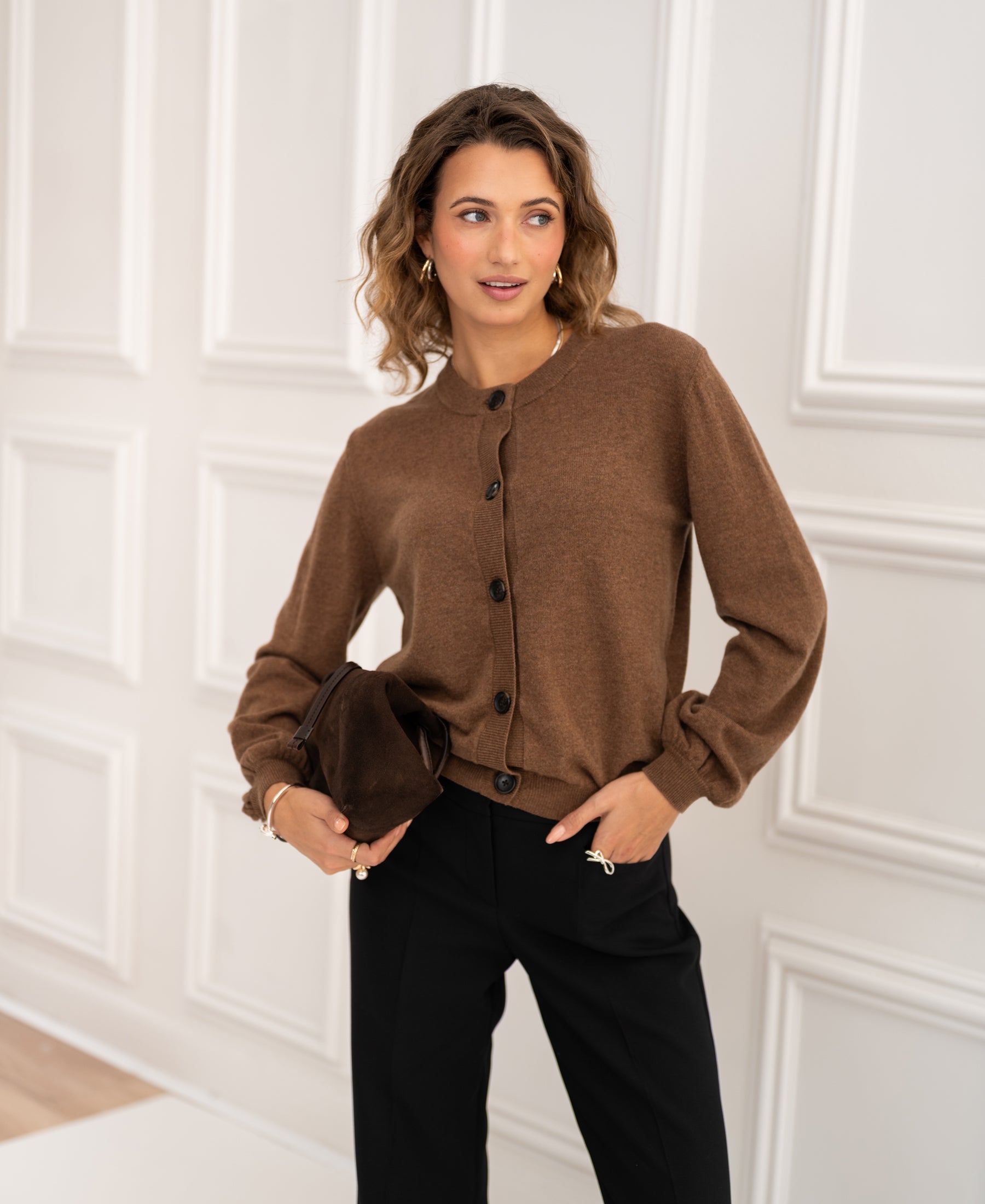 Crew neck cardigan LA LEA Tobacco by PLEIN PUBLIQUE, shown worn by a woman standing in front of white paneled doors.