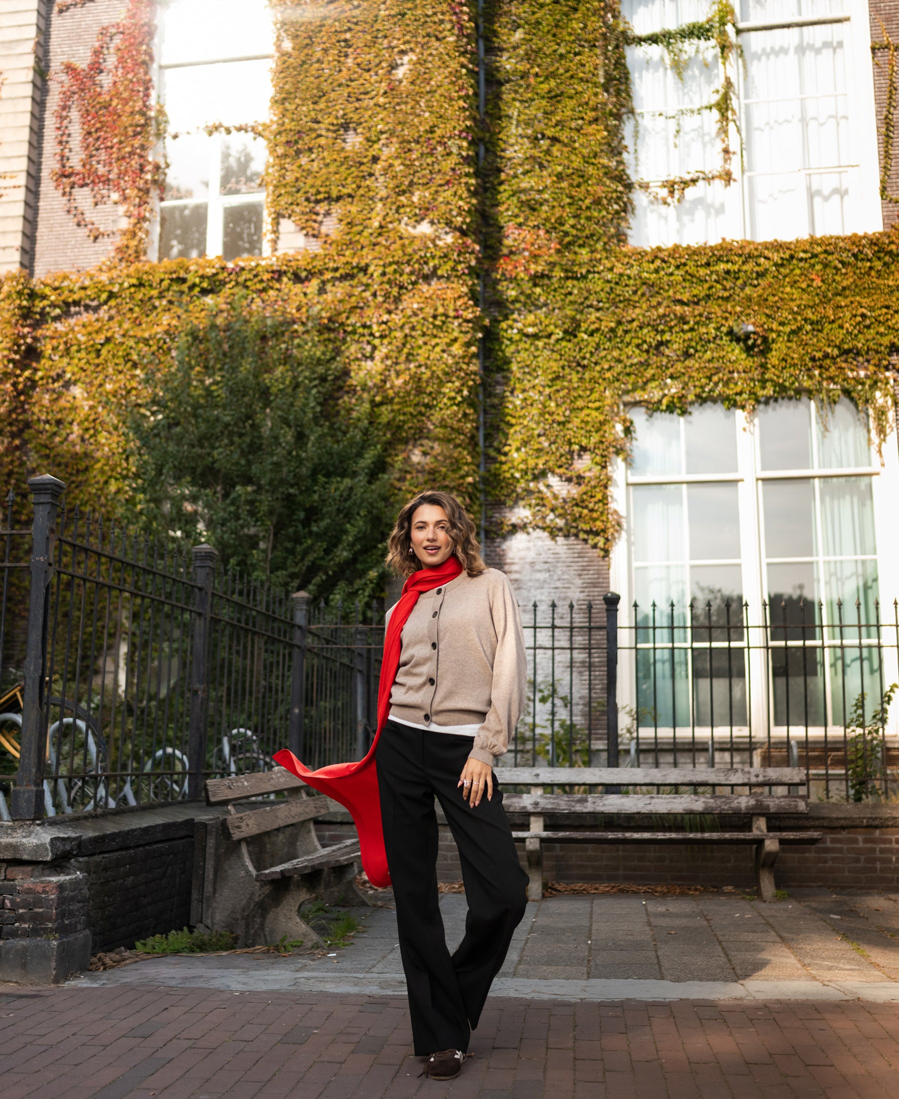 Coral-red merino wool wrap shawl shown outdoors near an ivy-covered building.