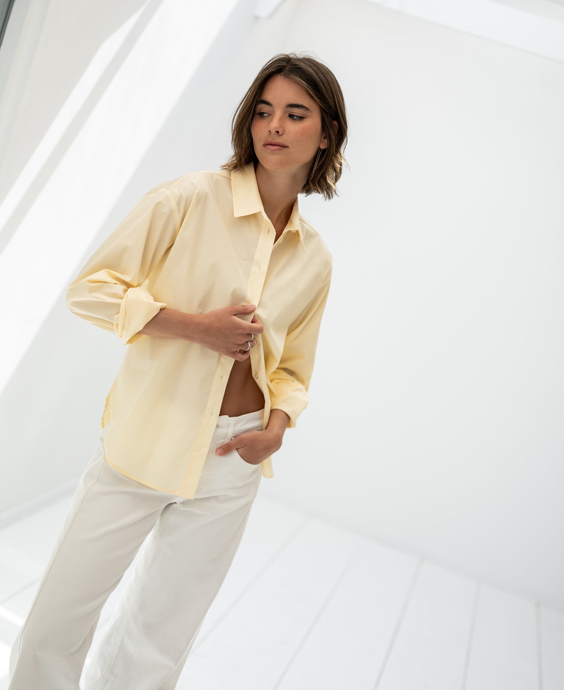 Oversized easy-iron soft yellow blouse in a bright, minimalist room.