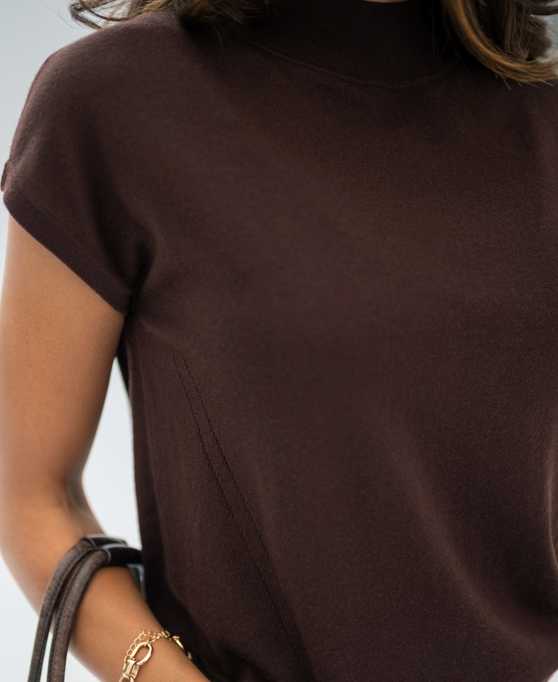 Woman wearing merino wool brown top, front view.