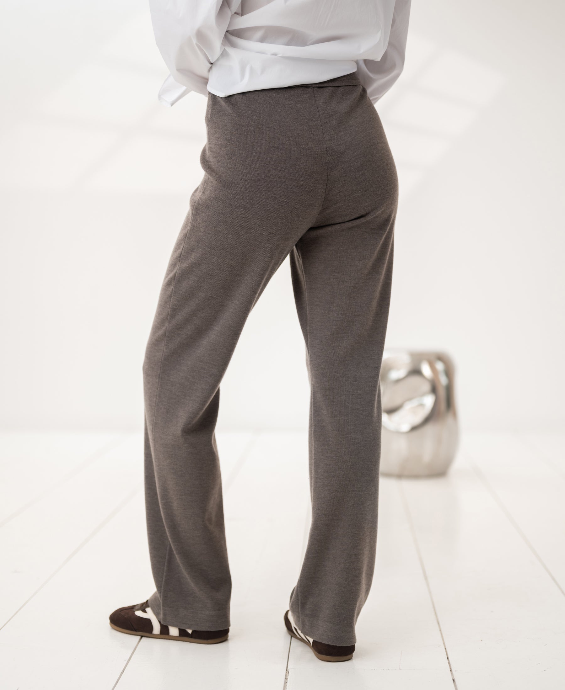 Dark sand knit pants on a white floor in a bright room.