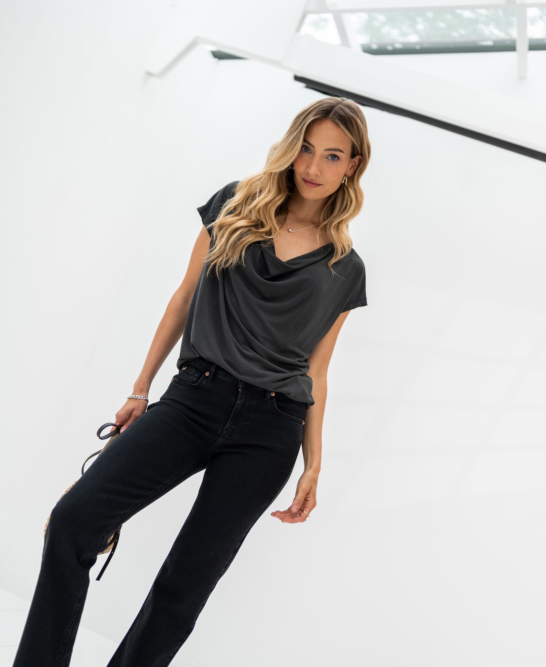 Charcoal grey cowl neck top in a bright white space.