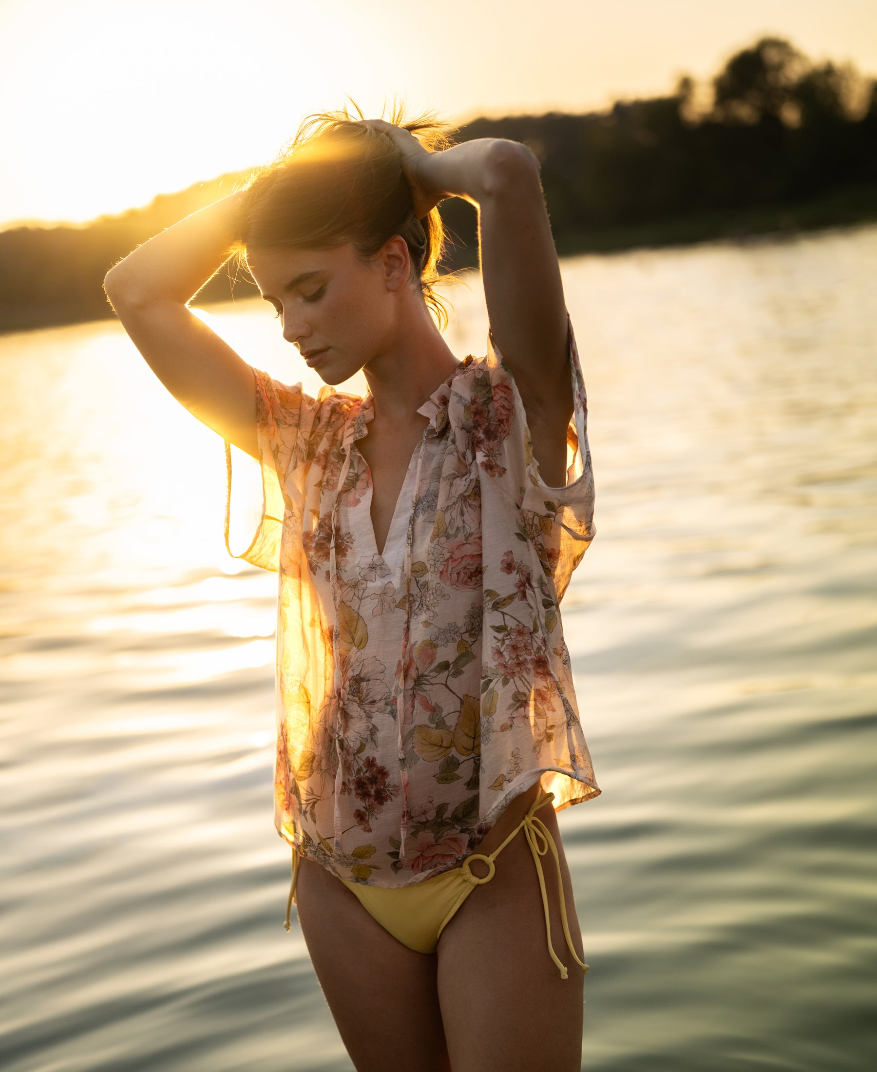 Woman (173cm, size S) wears a PLEIN PUBLIQUE blush floral print blouse top by the lake at sunset.