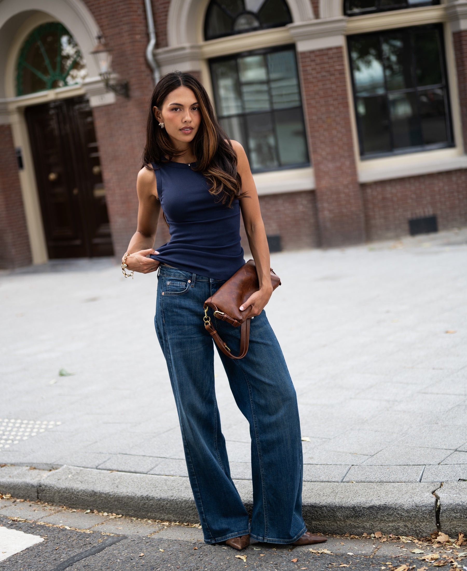 Woman wearing a luxe & soft dark blue LE LYS boatneck top by PLEIN PUBLIQUE, pictured on a city street.