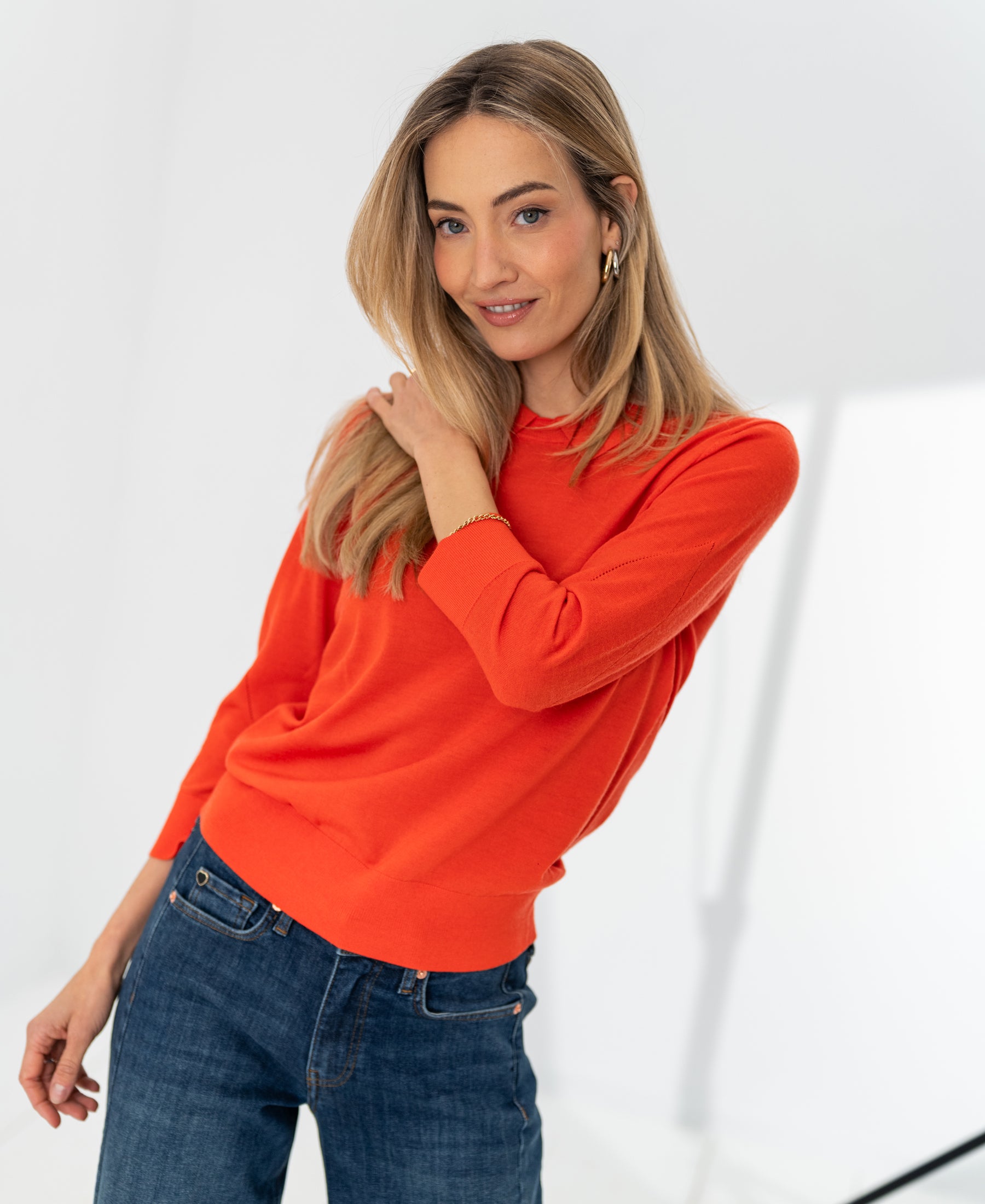 Coral red PLEIN PUBLIQUE LA MARCEAU merino wool sweater shown on model in a bright room.