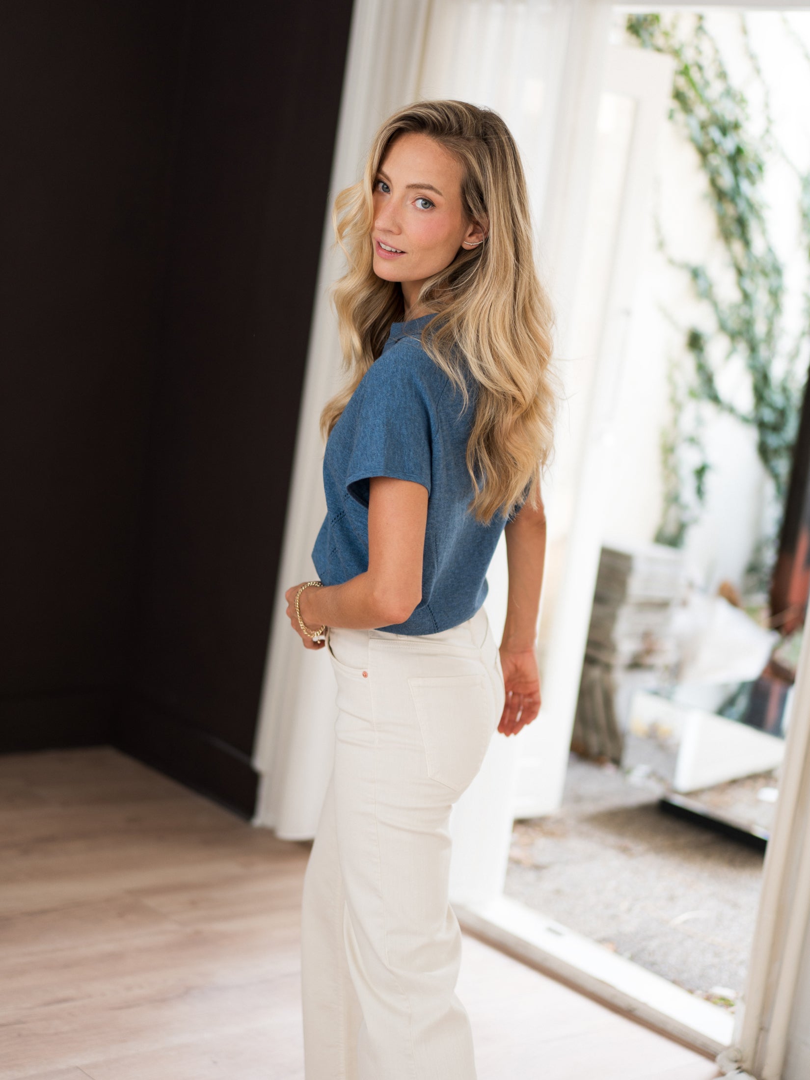 Woman wearing the LE MARTIN Polo Collar Sweater in denim blue from PLEIN PUBLIQUE, viewed from behind over her shoulder.