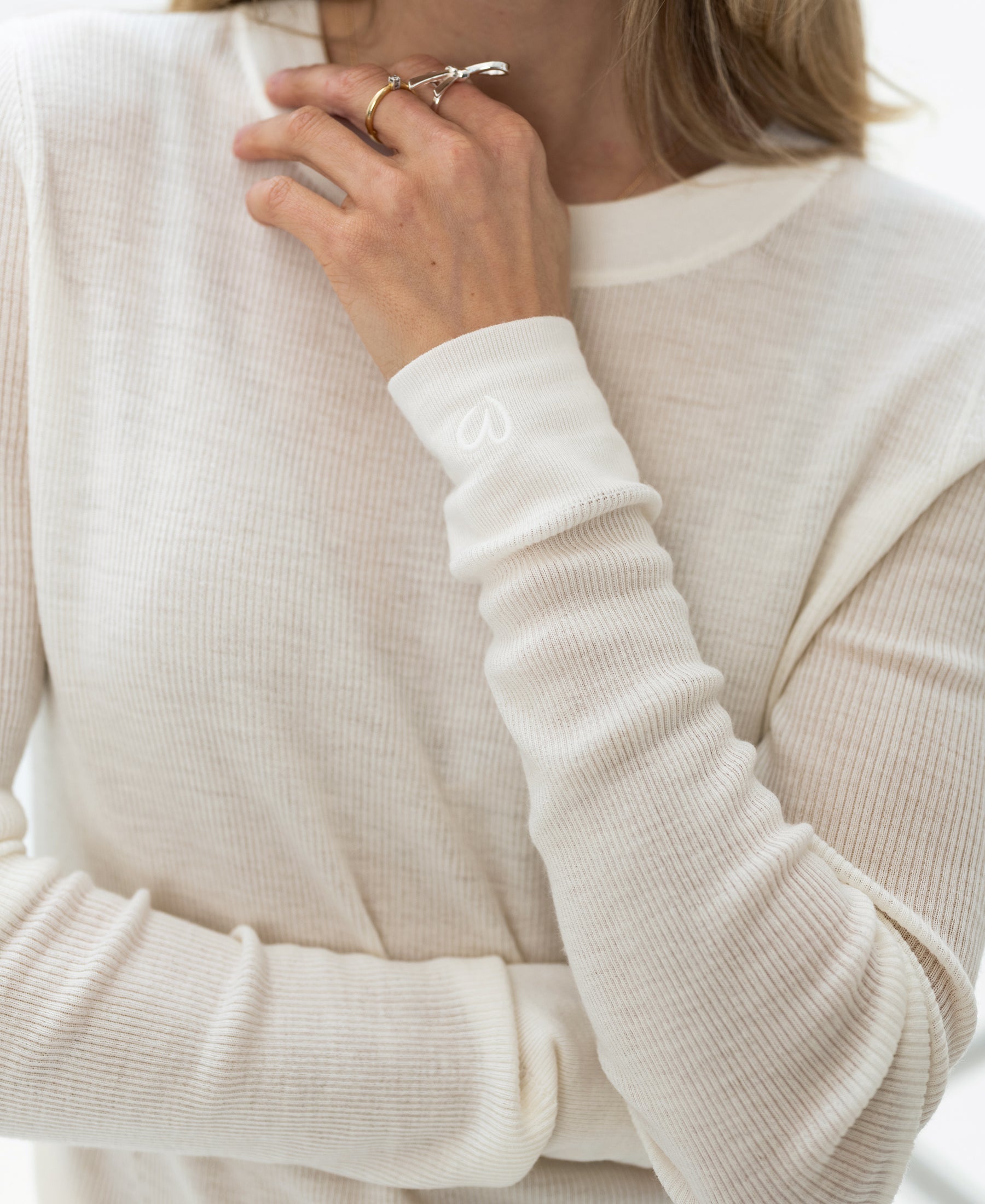 A person wears an ivory Luxe merino undershirt from PLEIN PUBLIQUE.