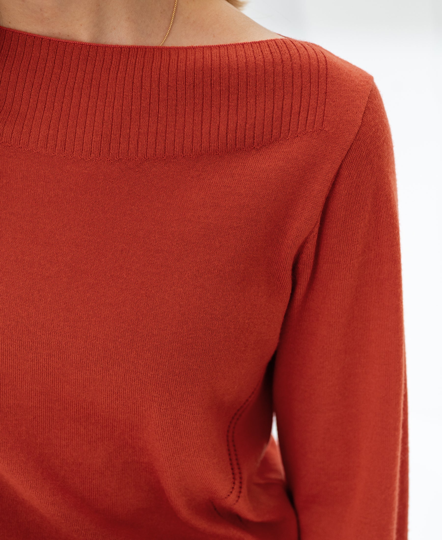 Shoulder-down view of a ribbed neckline sweater in cayenne, featuring a boat neck from PLEIN PUBLIQUE LA MUSE.