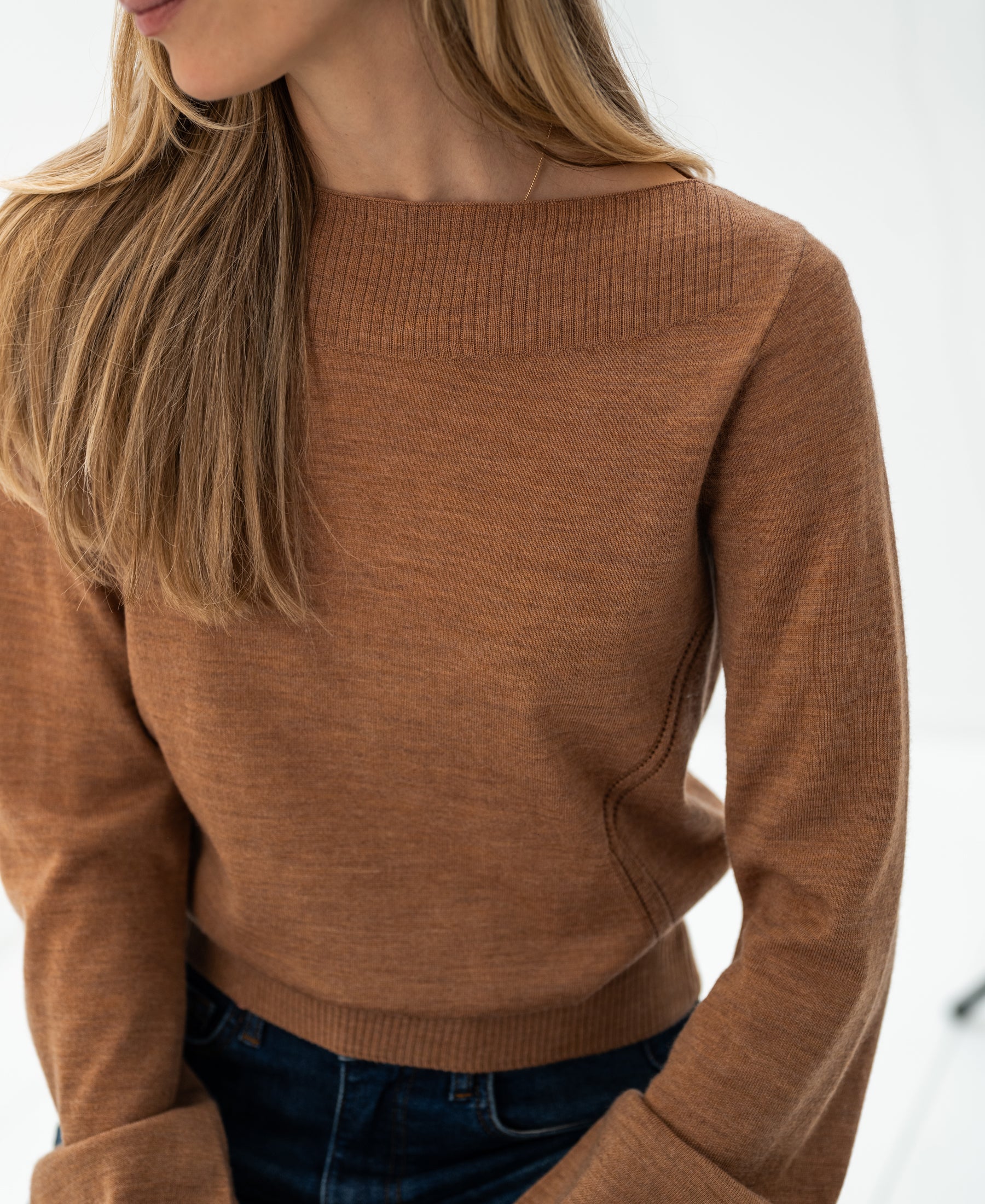 Vrouw poseert binnenshuis in de LA MUSE Chai tea boatneck trui van PLEIN PUBLIQUE.