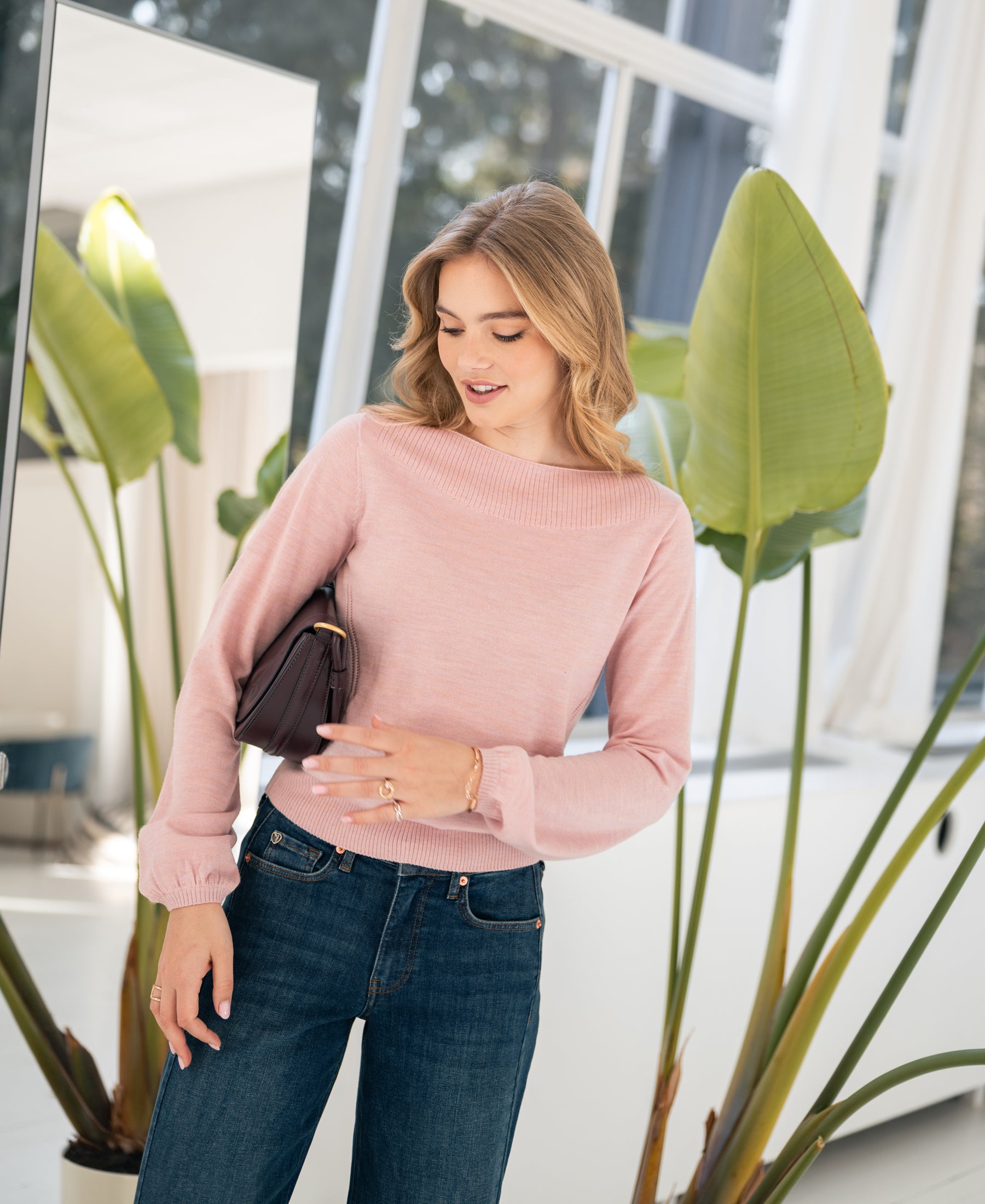 Vrouw draagt roze PLEIN PUBLIQUE LA MUSE trui met boothals, binnenshuis bij planten.
