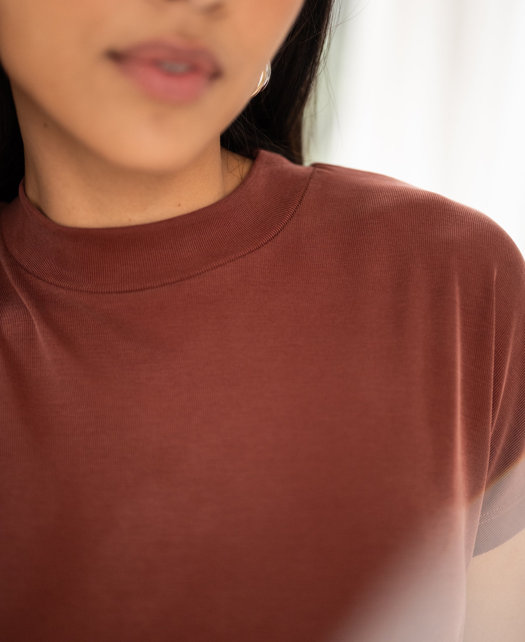 Ribbed collar top in henna color, shown from the shoulders up, face partly out of focus.