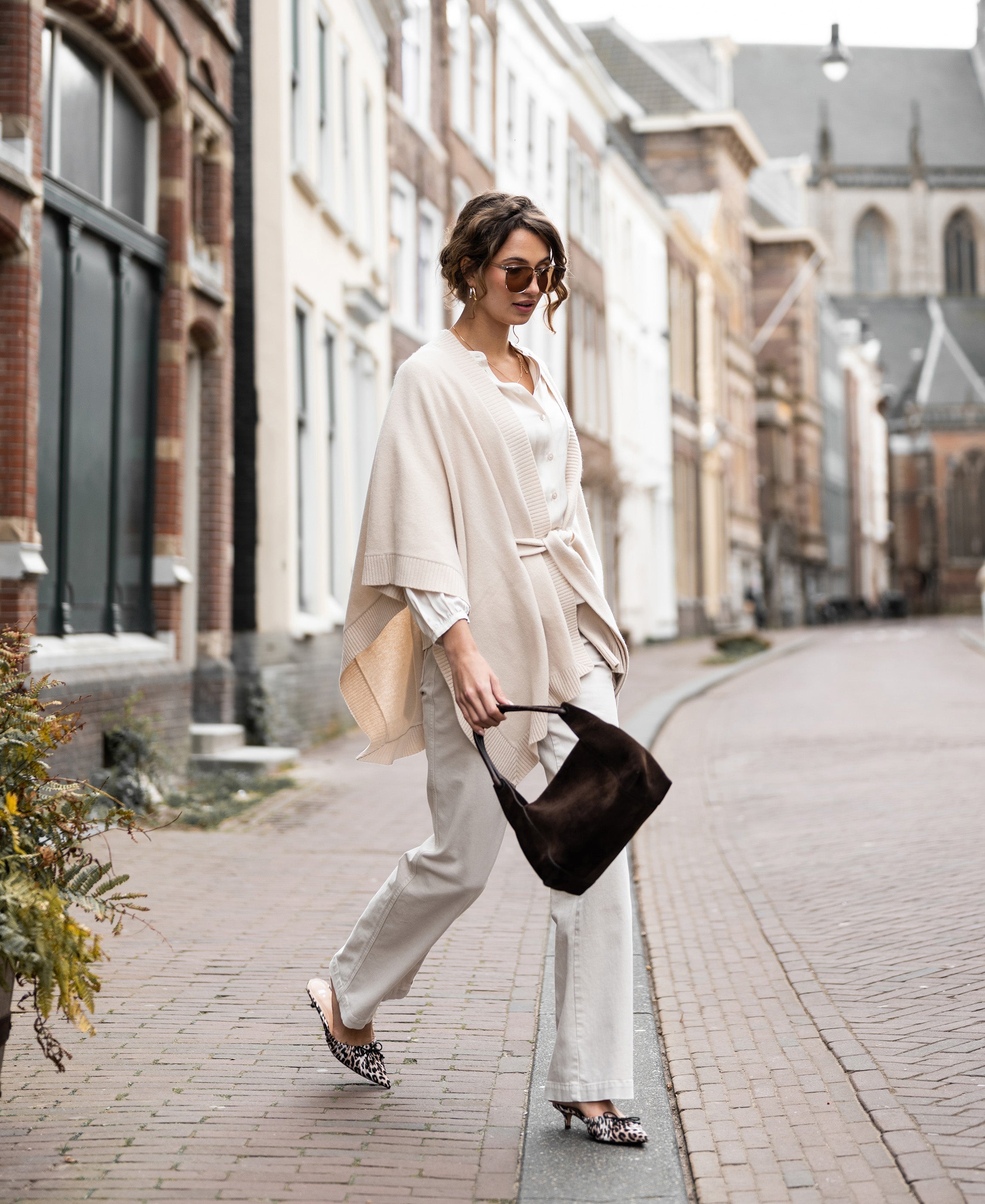 Light sand merino wool poncho by PLEIN PUBLIQUE, shown on a person outdoors.