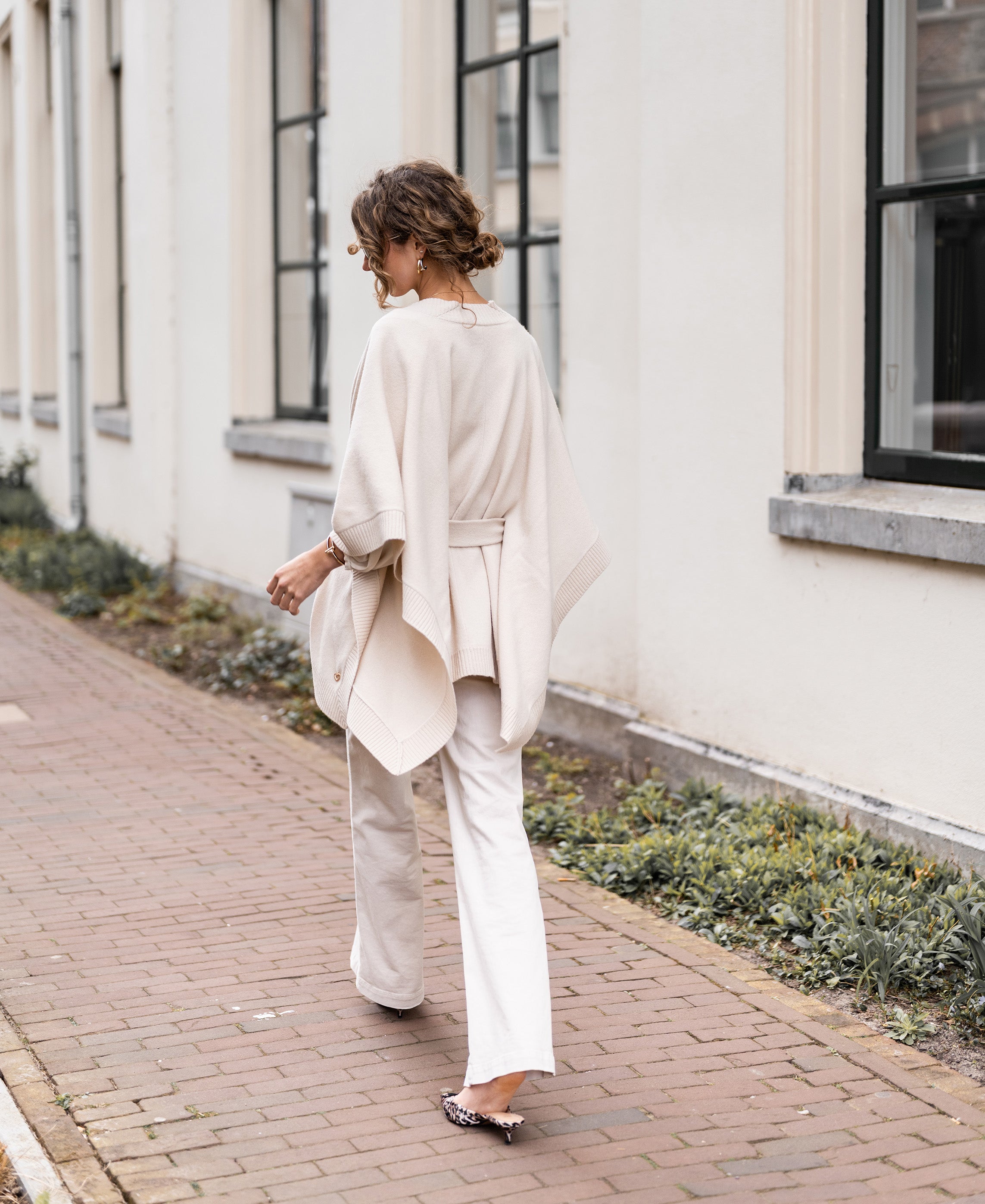 Light sand-colored merino wool poncho by Plein Publique, shown on a woman.