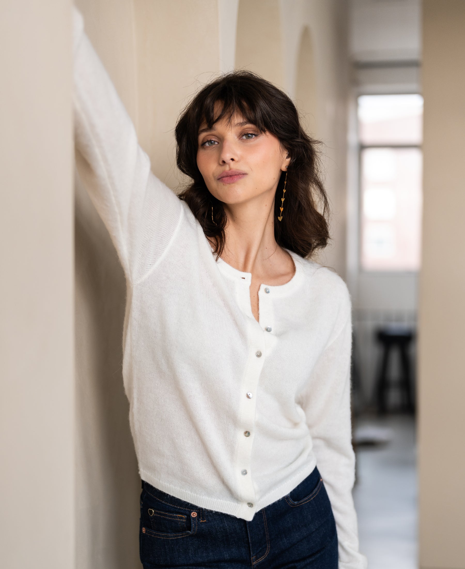 Ivory wool vest by LA QUARTE on sale, shown against a beige wall in soft light.