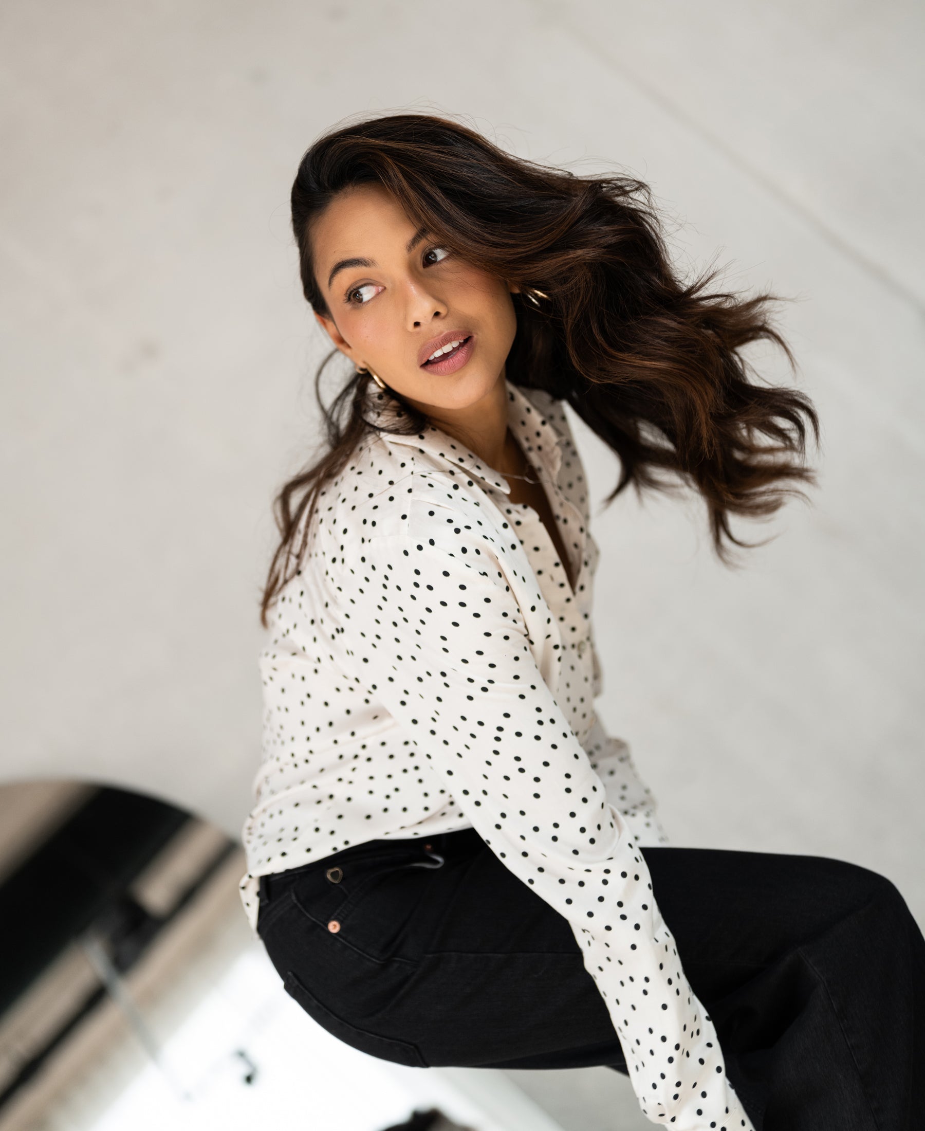 Ivory-black polka dot blouse by PLEIN PUBLIQUE, LA SEZANNE style, shown from the back indoors.